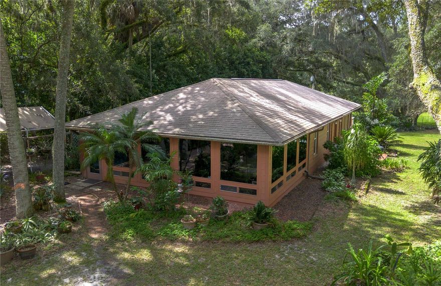 Tucked between the charm of Ocala and the energy of Gainesville, this 4.5-acre retreat in Citra is the perfect canvas for hobby farmers, homesteaders, or anyone seeking a slower pace in a private country setting. Tucked down a quiet, unpaved lane, this custom-built 2-bedroom, 2-bath home offers nearly 2,000 square feet of thoughtfully designed living space. Light and bright, the home invites the outdoors in through expansive windows that frame sweeping views of the surrounding countryside. The living area serves as a true focal point, where picture windows span two walls, highlighting the landscape while warm wooden tray ceilings add depth and character. A bonus of built-in storage enhances the room’s functionality. For those who enjoy cooking, the kitchen is well-equipped with plenty of cabinet storage, tile countertops, stainless steel appliances including a gas range, and a center island. Outdoors is where the property truly shines! Fenced and zoned A-1, the farm is well-suited for a multitude of uses including small livestock or equestrian use. A 2-stall barn is established with plenty of space for an additional 2 or more stalls. An additional shed, workshop, green house, and a cabana offer versatile utility with ample opportunity for further customization. Gentle shade can be found throughout the property from mature trees, including stunning oaks and some fruit trees. With a 2-car garage and an additional carport, there's room for equipment, trailers, or visitors. Whether you’re dreaming of farm-fresh mornings, space to grow, or just a quiet country backdrop with proximity to major cities, this property blends lifestyle and land with plenty of potential to make it your own.
