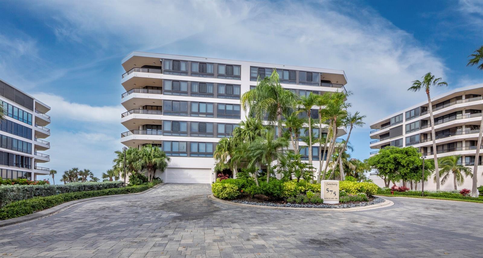 Renovated in 2023 and perfectly positioned on the 3rd floor, this 2BR/2.5BA residence at The Sanctuary offers a refined retreat where sweeping views and timeless design come together. Wood plank tile flooring runs throughout, while high-impact glass frames the vibrant greens of the Links golf course and the shimmering waters beyond. Neutral tones set an elegant backdrop, allowing the natural beauty outside to become part of the living space. The beautifully redone galley kitchen is both functional and stylish, with white cabinetry, stone countertops, stainless steel appliances and a charming eat-in area wrapped in floor-to-ceiling high-impact windows. The kitchen opens seamlessly to the living room where just beyond the wraparound terrace invites you to take in views that stretch across the Gulf, golf fairways and lushly landscaped Sanctuary grounds. Two en-suite bedrooms ensure comfort and privacy, including a primary suite that feels like a private sanctuary of its own. Floor-to-ceiling glass creates a dramatic view, while a custom walk-in closet with built-ins and a spa-inspired bath featuring dual vanities, a soaking tub and a glass-enclosed shower complete the retreat. Additional features include a laundry/storage room with full-size washer and dryer, plus a powder room for guests. The Sanctuary remains one of Longboat Key’s most coveted communities, offering residents 1,250 feet of private beachfront, under-building garage parking, 24-hour guard gate, on-site management, a heated pool and spa, Har-Tru tennis courts, a fitness center and more. Pets are welcome with restrictions. Additionally, while membership to the Longboat Key Club is not required, it is available for residents seeking enhanced amenities. The Club offers restaurants, lounges, beach & poolside facilities, spa, fitness center, tennis courts, and access to 45 holes of championship golf.
