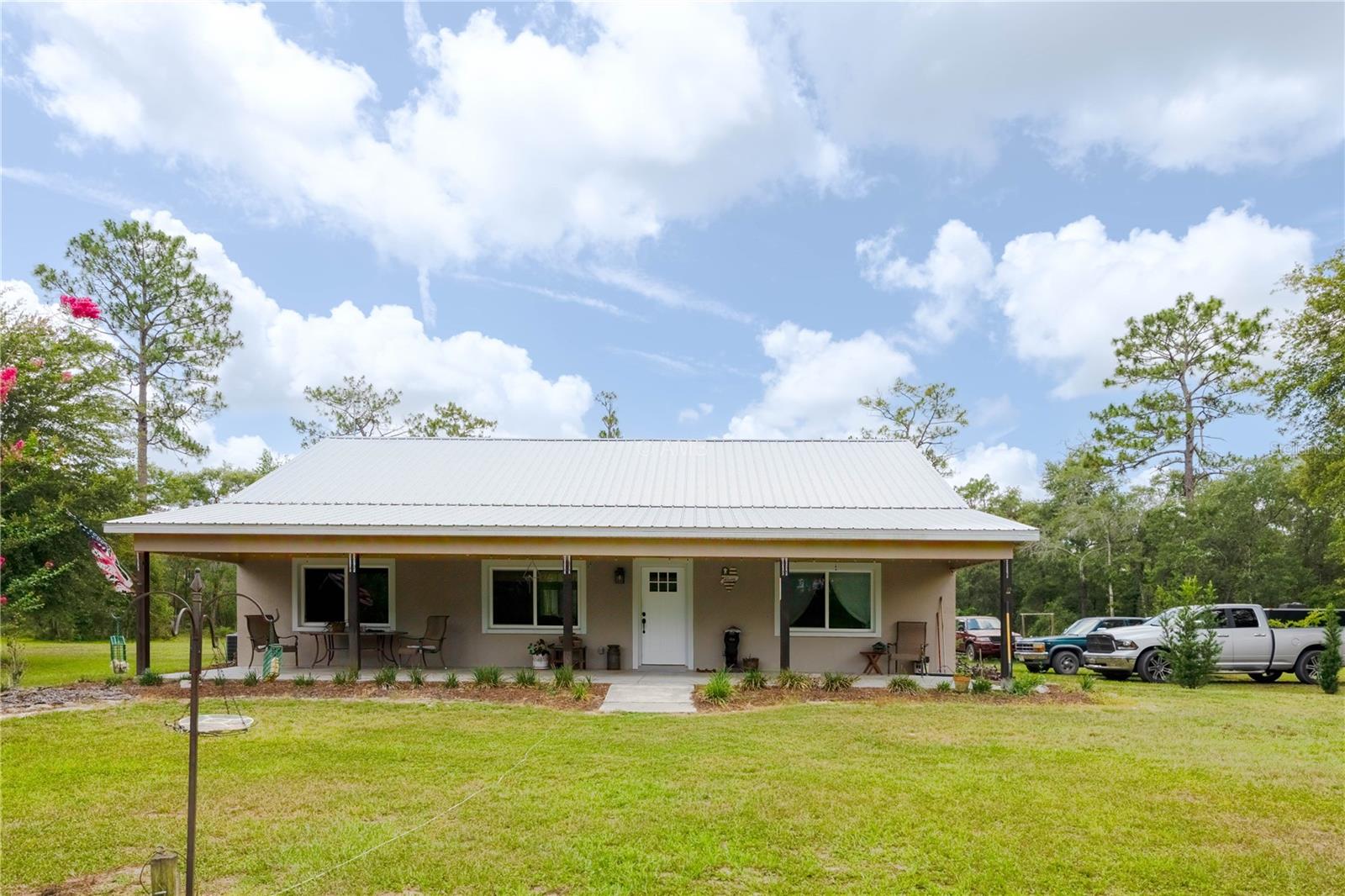 Welcome to your private slice of Florida paradise! Remember to take the full interior & exterior 360 tour right now! Situated on 5 fully fenced acres, this stunning property offers the perfect blend of peaceful country living and modern comfort. Enjoy your morning coffee or evening sunsets on the expansive front patio that spans the entire width of the home—an ideal spot for relaxing or entertaining. Inside, you’ll find a beautiful split-bedroom floor plan, an indoor laundry room, and a stylish, well-maintained interior. The metal roof adds durability and peace of mind, while the lanai and outdoor shower invite you to embrace the laid-back lifestyle. With plenty of room for horses and livestock, plus blueberry bushes and loquat trees, this property is a dream for nature lovers, hobby farmers, or anyone craving space and freedom. Come experience the charm and possibilities of this one-of-a-kind homestead!
