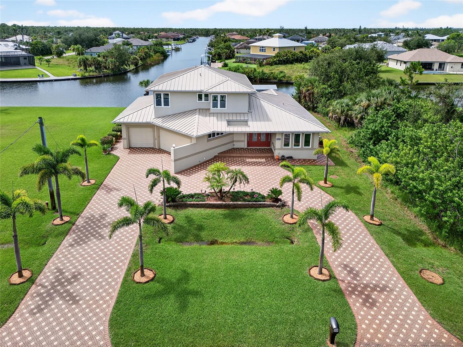DOUBLE LOT IN SOUTH GULF COVE! The adjacent lot is included and a great space to build a detached garage/workshop to store your boat, RV and all of your toys or build another home! This impressive 2-story property is a rare gem boasting 4 bedrooms, 3.5 baths, and a roomy 3-car garage, this home is perfect for those who desire sailboat access to Charlotte Harbor and the Gulf. Enjoy 170 feet of waterfrontage with stunning long and intersecting canal views, a composite dock equipped with water and electric, and a covered lift. Ideal for boating enthusiasts! Elevator access from the garage to the main and second floors makes for easy living and accessibility throughout the home. This home features a generous open floor plan with 3,250 square feet of living space. The great room is light-filled, with 3 sliders opening to the outdoors, perfect for bringing the outdoors in. Cook up a storm in the spacious kitchen with tons of custom cabinetry, granite counters, a breakfast nook, and a breakfast bar. Ideal for family gatherings. The primary suite offers lanai access and a private bath featuring a soaking tub and walk-in shower, providing a perfect oasis after a long day. The 2nd floor features guest suite or in-law suite, wood flooring, family room with large slider to balcony overlooking amazing water views and outdoor spiral staircase for quick access to pool. Outdoor entertaining area features covered lanai, cooking prep area, outdoor bath access, outdoor shower, screened heated saltwater pool and spa and paver uncovered patio to dock with true southern exposure so guests from the north can enjoy and abundance of sunshine. Additional special features include metal roof, high impact glass, electric roll down shutter on lanai, security system, central vacuum, large first floor laundry with sink and cabinets for storage, freshly painted interior, paver circular driveway, outdoor shed and mature tropical landscaping. South Gulf Cove community offers voluntary HOA with clubhouse for special events, four parks nearby including South Gulf Cove Park and Boat Ramp and close to fine dining, shopping, parks, numerous golf courses, boating, and a short drive to Boca Grande and Don Pedro Island beaches. This beautiful home is move-in-ready and perfect for a growing family. Schedule your private showing today!