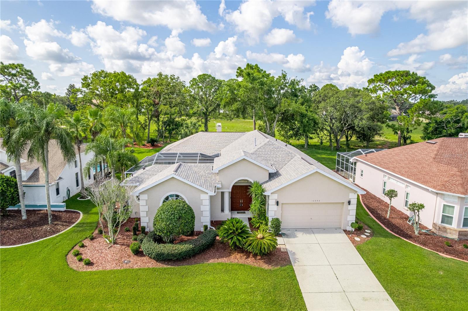 Welcome to this popular Cabana-style pool home located in the desirable Seven Hills Golfers Club Estates, an upscale community in Central Florida. This thoughtfully designed 3-bedroom, 3-bathroom residence with a 2-car garage offers exceptional privacy and comfort, ideal for multi-generational living or entertaining guests. The home centers around a stunning screened-in pool courtyard with waterfall feature and a fully equipped outdoor kitchen with a JennAir grill, bringing the ultimate in Florida indoor-outdoor living.
The spacious floor plan includes a bright and open living room with a cozy gas fireplace and brand new wood-style flooring, a formal dining room with built-in cabinetry and display shelves, and a separate family room that opens to a rear lanai overlooking a serene no-build area. The kitchen is designed for both function and style, featuring a gas cooktop, center island, desk nook, breakfast bar, and casual dining space. The third bedroom and private bath are situated apart from the main living areas, ideal for in-laws, adult children, or visiting guests.
The primary suite offers a generous walk-in closet with built-ins and a private view of the pool area. Additional features include a spacious interior laundry room with sink and cabinetry, freshly painted interior, and a brand new roof installed in August 2024. With low HOA fees and located in a premier community, this home offers luxury, convenience, and value—don’t miss the opportunity to make it yours.
Beyond the home’s borders, a wealth of recreational opportunities awaits, including nearby attractions like the renowned tarpon fishing waters of the Gulf of Mexico, nearby Tarpon Springs sponge docks, and scalloping hotspots. Outdoor enthusiasts will love the access to kayaking, tubing, miles of bike trails, horseback riding, and motocross. The area also offers numerous golfing options and convenient access to shopping, dining, and medical facilities along Hwy 50 and US 19. Additionally, the home’s proximity to major highways ensures easy travel to Central Florida’s theme parks, Tampa’s cultural attractions, and both Tampa International and Saint Pete Airports. Top-notch healthcare facilities, such as Tampa General Hospital, are also within close reach.