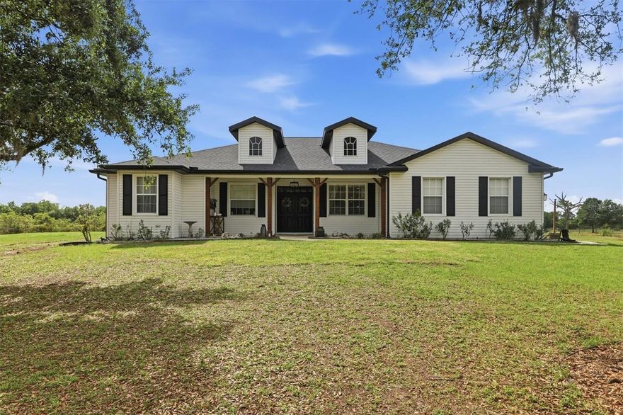 Country living at its finest! Set on 5 private acres with a NEW ROOF (2025), NEW AC systems (2024 & 2025), a horse pasture, a 3-bay outbuilding, and NO HOA, this spacious 3-bedroom, 2.5-bath home opens the door to a lifestyle that feels bigger, more free, and far more exciting than the ordinary. Step inside to a foyer framed by a formal dining room and a separate den. The dining room is ready for holiday dinners, hosting friends, and everyday meals, while the den offers a flexible space that easily works as an office, playroom, guest room, or a dedicated spot for hobbies and projects. Just beyond, the main living room centers around a double-sided fireplace and sliding glass doors to the lanai, creating a space where the fireplace becomes the focal point for conversations or winding down at the end of the day. The kitchen sits at the heart, featuring newer cabinetry, ample countertops, stainless steel appliances, a pantry, and a wraparound breakfast bar that gives you plenty of room to enjoy a snack, do homework, or prep food. The casual dining nook sits beside bright windows, perfect for your morning coffee or a quick lunch. Beyond, the second living area becomes an easy place for watching sports, playing board games, or catching up at the end of the day. The bonus room adds a completely different kind of space, complete with a built-in bar and cabinetry that naturally sets it up for entertaining—add a pool table, poker table, lounge seating, or turn it into a theater room. The primary bedroom is positioned privately, creating a retreat with direct access to the lanai and the added warmth of the double-sided fireplace. Two closets—including a large walk-in—provide ample storage, while the COMPLETELY UPDATED en suite bathroom features dual vanities, a soaking tub, and a separate glass-enclosed shower, creating a space that feels elevated and well-appointed every day. Two additional bedrooms and a full bathroom are located on the opposite side of the home, forming their own wing with space for kids or guests. The laundry room is set up for convenience, with a utility sink, cabinetry, and counter space. The home also includes a 50-amp transfer switch for an exterior generator, NEW exterior paint, and NEW aerators on the well, adding to both function and long-term reliability. The oversized screened lanai stretches across the back of the home, giving you a true outdoor extension with space for dining tables, lounging, grilling, and a hot tub that turns time at home into something you truly look forward to. From there, the property opens up into 5 acres that invite you to use every part of it—spend time at your own private shooting range, ride 4-wheelers, have a firepit night with friends, cast a line from the dock at the pond, or design your own setup with a pool, slide, or outdoor kitchen. For horse enthusiasts, the groundwork is already in place with approximately one acre fenced pasture, 2 horse stalls and a tack shed, and well water to support it all. The 3-bay outbuilding adds serious capability with 150-amp service, a 30-amp RV hookup outside, and well water—ideal for equipment, storage, workshop space, or keeping everything from trailers to tools organized and ready to go. This is a RARE opportunity to own 5 sprawling acres with NO HOA restrictions—an exceptional property that gives you the space, privacy, and complete freedom to live without limits, to shape the land around your lifestyle, and to create something truly your own.
