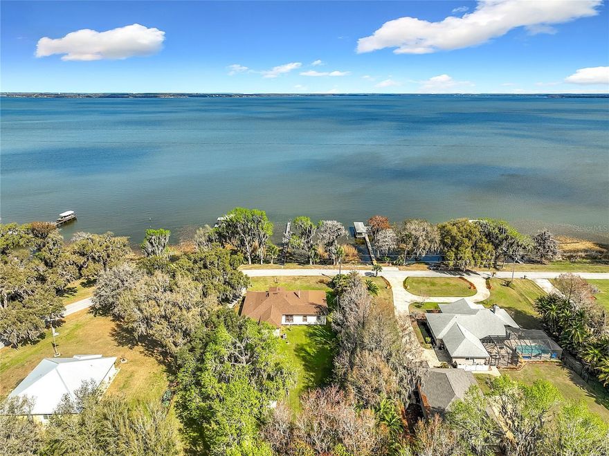 Historic 3BR/2BA Lakefront Retreat with 120 Feet of Waterfront - Discover the charm of Southern living in this rare historic residence perched above the shimmering waters of Lake Harris in the peaceful lakeside enclave of Yalaha. Set along Lakeshore Drive, where homes seldom become available, this 4-bedroom treasure embodies the romance of 1920s Old Florida with sun-filled interiors, vintage wood floors, stately columns, and a classic brick fireplace. Begin each morning with golden lakefront sunrises from the expansive screened Florida room, and spend your days on the water—kayaking, boating, or simply relaxing from your private dock. As evening falls, savor sweeping sunset views from the generous wraparound porch, where warm breezes drift across your 120 feet of pristine shoreline.

The custom kitchen blends craftsmanship and comfort with handcrafted cabinetry, a cozy eat-in nook, and an adjoining mudroom. Formal living and dining spaces embody timeless sophistication, perfect for intimate gatherings or showcasing a grand piano.

Ideally located minutes from the beloved Yalaha German Bakery & Beer Garden, the spa and golf amenities of Mission Inn Resort, and the charming towns of Mount Dora, Tavares, and Eustis, this home offers a rare blend of history, elegance, and recreation.

With no HOA, you’re free to bring your boat, RV, and all your toys. A truly exceptional lakefront offering—schedule your private showing today and experience the finest in classic Florida living.
