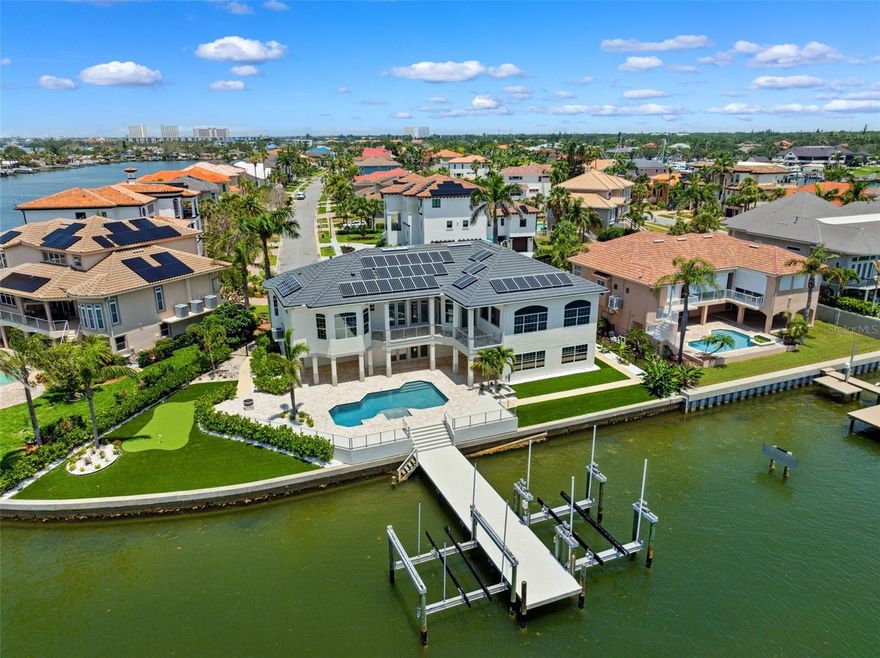 Welcome to your dream oasis in Pasadena Yacht & Country Club! This exquisite waterfront home has been meticulously remodeled to cater to the modern buyer, offering a rare find for those who harbor a passion for both boating and car collecting. With 160 feet of protected waterfront, this residence features a stunning large dock equipped with an impressive 50,000lb boat lift and an additional 24,000lb lift, making it a boater's paradise. The outdoor living spaces have been masterfully reimagined, boasting an expansive extended travertine and composite deck, sleek stainless steel cable railings, and low-maintenance artificial turf. Enjoy endless entertainment with a private putting green, cozy firepit, and more! Car enthusiasts will marvel at the expansive garage, complete with epoxy flooring, an interior remote garage door extending the space, and a temperature-controlled environment perfect for special vehicles, a gym, and a cabana room. Elevated to perfection, this well-built home offers low transferrable flood insurance as well as an elevator, and state-of-the-art solar panels. The newly remodeled chef’s kitchen is a true delight for entertaining, featuring modern flat-panel cabinetry, a contrasting color island with natural gas cooking and prep sink, a Sub-Zero refrigerator, built -in Meile coffee maker, exquisite granite countertops, and a breakfast bar overlooking the family room and waterfront. High volume ceilings, elegant crown moldings, and floor-to-ceiling doors and windows allow natural light and stunning water views from most rooms. The custom layout includes formal living and dining areas, a split-bedroom plan with a luxurious primary suite featuring a newly remodeled en-suite bath, dual vanities, an expansive frameless glass shower, and a custom walk-in closet. The opposite wing of the home hosts a waterfront guest suite with a remodeled bath, two spacious additional bedrooms, a beautifully updated shared bath, and a private den, perfect as an office or playroom. All living spaces are conveniently situated on one level, with additional upgrades like a new expanded travertine driveway, fresh exterior and interior paint, and much more! As a resident, you'll have the privilege to join the Pasadena Yacht & Country Club without a waitlist (if you join within the first 30 days of ownership). PYCC stands as the only gated community in Pinellas County offering both a golf course and boatable waterfront. Enjoy a remodeled 18-hole golf course, fitness center, waterfront heated lap pool, fine and casual dining, as well as tennis and pickleball. Seize the opportunity to have it all in this unparalleled waterfront experience!