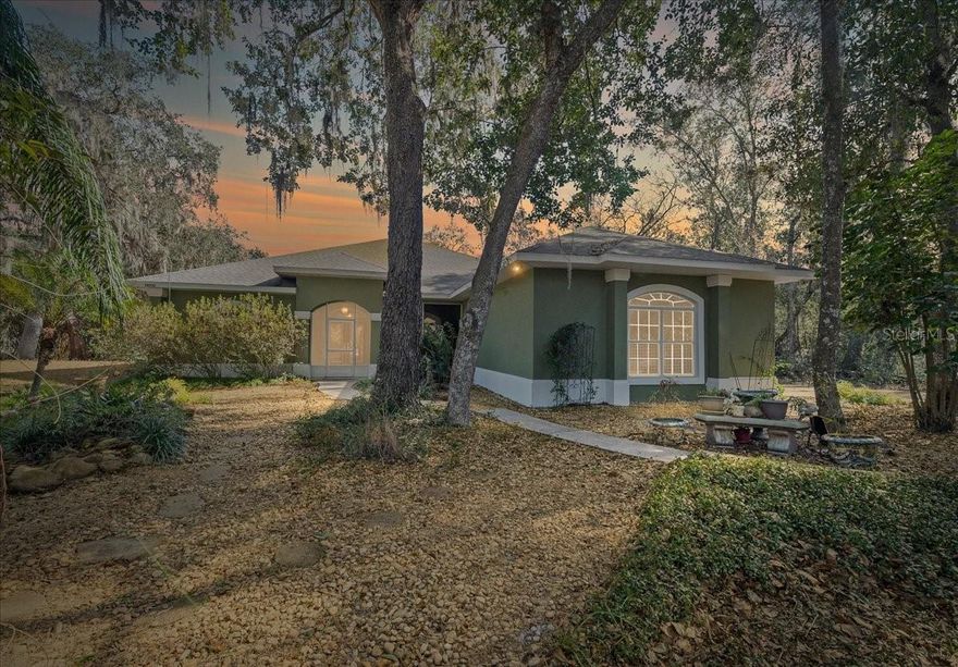 Live the Florida dream in this gorgeous 3 bedroom, 2 bath pool home on 2.83 acres of peaceful, agricultural zoned land, perfectly situated on a quiet dead end road. With 2,288 sq. ft. of spacious living, this property offers a private oasis with waterfront canal access and the unique opportunity to enjoy all that Florida’s beautiful Chain of Lakes has to offer. Whether you love boating, kayaking, or simply relaxing by the water, this home has it all. Step through the front screened in porch and into the dining area that flows seamlessly into the living room, highlighted by a cozy wood burning fireplace, natural light throughout and custom built in shelving. The large kitchen is a chef’s delight, featuring abundant cabinet and counter space, a functional layout, pantry and an additional eating area for casual meals or morning coffee overlooking your serene surroundings. Oversized primary suite creates a true private retreat, complete with a cozy seating area and a spacious walk in closet. En suite bathroom features dual vanities, a walk in tiled shower, and an soaking tub, an ideal place to unwind after a long day. The split floor plan ensures privacy for guests, with two additional bedrooms and a guest bathroom located on the opposite side of the home. One of the home’s standout features is the large, covered, screened in pool area, complete with a solar heated pool, spa, and views of the canal and property. The property also includes a Koi pond, adding charm and serenity, and plenty of space to build a barn, garage or additional outbuildings to suit your lifestyle. For water enthusiasts, the canal provides direct access to the Chain of Lakes, making it easy to launch a boat, kayak, or canoe and explore miles of scenic waterways. The home has been well maintained with a New roof and HVAC system installed in 2020, Pool resurfaced in 2019 and even comes with a 1 year home warranty at closing for added peace of mind. Despite its private, tranquil setting, the home is conveniently located near The Villages, offering quick access to shopping, restaurants, entertainment, and hospitals. This home truly offers a rare combination of privacy, functionality, and Florida waterfront lifestyle. From relaxing in your solar heated pool and spa, to exploring the canal, to simply enjoying the spacious grounds and natural beauty, this property is a dream come true for anyone looking to embrace the best of Florida living!