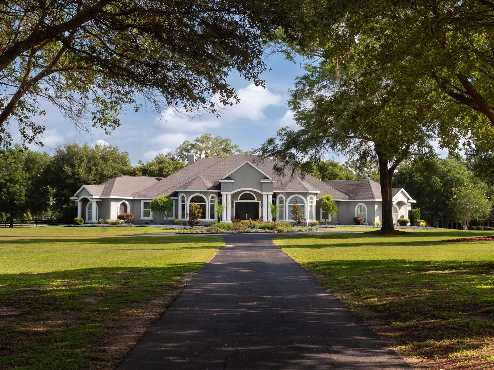 This meticulously-maintained 21+ acre farm is located deep in the heart of NW Ocala's Horse Country just 15 minutes to the WEC! The farm includes a 10-stall main barn with hot/cold water, washracks, fly spray system, indoor laundry, and an over-sized office/tack room. Auto-water, feeders, hayrack system, new stall doors have been recently added, as well as a separate gated paved entrance to the barn from the main road. A second barn has been added which features 4 stalls, auto waters, feeders, a/c tack, lights with timers, feed room, and an RV hookup with 30 amp and 50 amp. The farm also features a fully irrigated mirrored Wordley Martin arena with GGT footing, and a new 100x200 sand arena. Other improvements include a viewing gazebo, hot walker, round pen, stop fence, and automatic water in the pastures. The luxurious home boasts high ceilings, tons of windows, gas fireplace, gorgeous kitchen with stainless appliances and gas range, and a huge en suite main bedroom with enormous walk-in closet. An inviting open floor plan spills out onto the lanai and pool area through an expanse of glass doors. Recent pool area improvements include new heater and new pool enclosure. Landscaping has been refreshed, trees removed, septic tank replacement, and many other upgrades have been made. This is a move-in ready farm with all the bells and whistles!