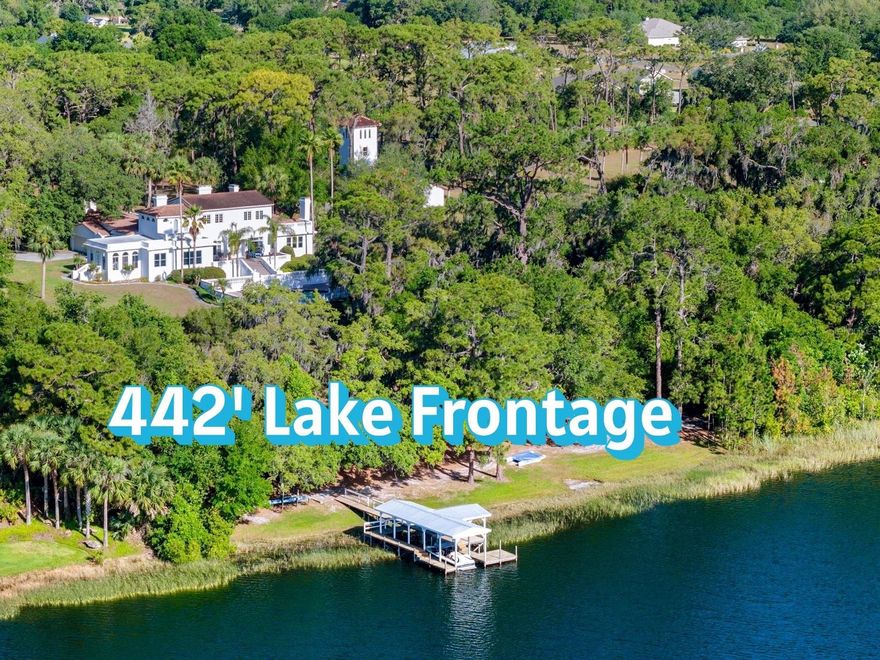 Come, step back into time to a magnificent waterfront Mediterranean estate that is perfectly positioned on 6 acres and 442 feet of direct frontage on pristine spring fed Lake Dalhousie where residents enjoy swimming, fishing, boating, water skiing and kayaking. A true retreat from the city life and one of the prettiest areas in Lake County. It enjoys the best of both worlds, uncrowded, peaceful country living, but close to shopping, major highways and the beaches. The grounds are enchanting but become sublime as you take in the spectacular early morning sunrise and golden hour that reflects on the home in a rich fairy tale glow. Stroll through the grounds where you will find stately grandfather oaks, bricked walkways, 1926 domed pavilion and emerald lush gardens all irrigated from the lake. You will notice the original 4-story water tower which, is no longer in use but stands tall capturing attention, making it one of the homes most iconic features. Commissioned with grandeur and built to endure in 1926 by Dr. Edgar J. Banks, a noted archeologist who began coming to Eustis in 1916 and today, this spectacular Mediterranean is ready to celebrate her 100th year old birthday. A peaceful courtyard entry with a stately fountain, loggias and Mahogany glass door entry add to the excitement and hint at the elegance within. Approximately over 6,200 square feet of living area consist of 2 master suites, 4 guest bedrooms and 5 1/2 baths. Upgraded plumbing and electric, volume ceilings, graceful arches, beautiful oak wood flooring, ornate fireplaces, large baseboards, iconic chandeliers, original Tudor style windows and newer windows that include Pella, Andersen, Marvin and Jeld-Wen, blend period charm with newer and modern conveniences. The grand ballroom overlooks the lakefront and features large parquet flooring and cherry wood inlay. The volume ceilings are graced with beautiful chandeliers, decorative hand carved plaster border and showcased with a handsome Artisan European gas fireplace. French doors open wide to the outdoor terrace which overlooks the 20x40 inground pool with stone paver decking, and mesmerizing views of the lake. The formal dining room features parquet flooring, Tudor style windows, coffered ceilings and original gas fireplace with a white mantle that has been delicately carved with the words Dolce Far Niente, meaning Sweetness of Doing Nothing. The generous kitchen, breakfast room and family room overlook the lakefront and have been completely redesigned with oak flooring, Quartz countertops, stainless steel appliances, French Country cabinetry and marble backsplash. The exterior back of the home stands tall and magical and features a magnificent focal point, designed with an abundance of white balustrades, the 20x40 inground salt pool, a terrace that spans the back of the home and a private master suite second story balcony. Perfectly designed for grand scale entertaining or tent the lawn for a beautiful outdoor wedding. The back yard features a gentle slope to the lakefront with long extended dock and a boathouse that currently houses a 21-foot boat and room for another. The main house features a 2-car garage, and another 4-1/2 car garage was added to the 4-story water tower. Other highlights include a very clean and neat large basement with upscale Kinetico water system and other mechanicals. This is a rare opportunity to own an original and architecturally stunning Mediterranean period home that seldom comes to market.