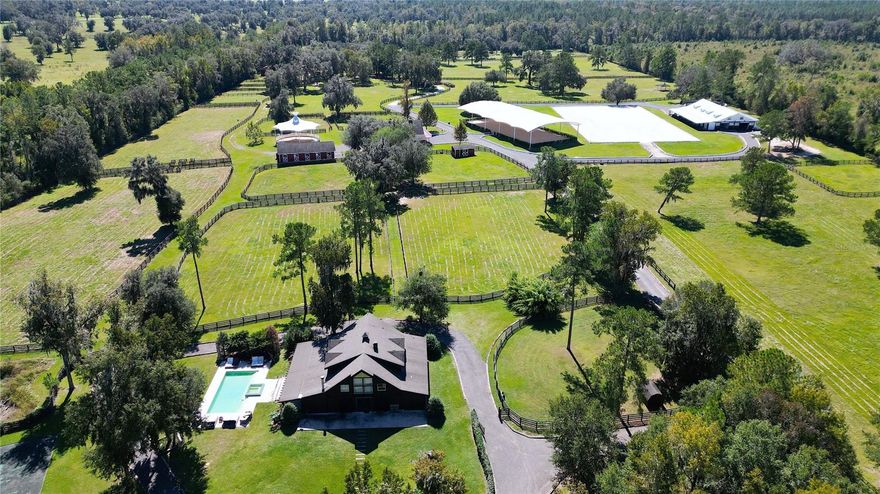 Under contract-accepting backup offers. State-of-the-art 54-acre equestrian facility – Great Location – 20 Miles from the World Equestrian Center with incredible amenities. This property has it all: Luxurious yet rustic main residence overlooking the beautiful in-ground pool, spa, and tennis court. The enchanting primary residence is an entertainer's dream with 4,600+ SF of living area, 5 bedrooms, 5 1/2 baths, and has everything you need! Enter the 2-story residence with luxurious and intricate woodwork throughout and discover spacious living! The stunning chef’s kitchen features: commercial range, venta-hood, two dishwashers, plenty of cabinet space, plus a large center island for seating family or guests all is open to the dining and living areas. The dining area easily accommodates a table for 12 or more guests and offers great pool views. The family area features a real wood-burning fireplace. There are 3 spacious guest bedrooms and 3.5 baths on the main floor. All the space on this side of the home looks out with many  doors and windows overlooking the back lanai and the lush, green, and serene backyard. Tons of natural light abounds throughout! On the second floor, the expansive primary suite is a private retreat featuring a fireplace that provides a cozy ambiance, another ensuite bedroom, den,  and bonus room. The private pool area is perfect for relaxing and enjoyment of poolside fun. Additional improvements include: Two private 1/1 guest quarters, a detached 4-car garage, A show stable featuring 17 oversized stalls, a large overhang entertaining/viewing area, on one side overlooking the outdoor arena, 2 baths, wash stalls, plus an upstairs entertaining lounge and viewing area with a full kitchen. Outdoor round pen. The second barn has 6 stalls, a large tack and feed room, a bath, an apartment upstairs, a storage room, and an employee lounge area.  Plus separate office. The third barn offers 5 show stalls with rubber paver aisles, a separate 2-foaling stall barn, and a covered round pen. An oversized covered arena with professional footing, irrigation, and light for night riding. The outdoor arena measures 130’ X 230’. Perfect for dressage or jumping.
The equipment building is perfect for large RV's, trailers and equipment. Many large, shaded paddocks with run-in stalls and open pastures for horses, mares or foals. Lush green pastures, mature landscaping, and Granddaddy Oaks make this property a beautiful setting you will enjoy and want to share with your clients, friends, and family. Whether your passion is hunters, jumpers, Thoroughbreds, or any other horse breed, the farm offers room to ride, train, and raise horses. This is a one-of-a-kind equestrian facility. This farm offers unlimited potential in the Horse Capital of the World and great income potential.