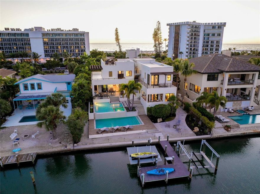 In a world where more is usually never enough……. 161 S. Polk Drive is JUST ENOUGH and MORE OF EVERYTHING YOUR DREAMS ARE MADE OF!   Positioned waterfront between St. Armands Circle and Lido Beach, you can start your day walking just one block to put your toes in the sand and soak up the morning sun and then head straight to your favorite lunch spot on the circle.  Upon returning home, take up lounging in the split-level, salt water pool and relax to the sounds of the water as it crests the infinity edge OR you can choose one of the many decks, from rooftop on down, canal to Gulf, to savor the sun, the breeze, the views and the peacefulness all around you.  Once evening arrives, hop on the boat for a pleasant ride to your waterfront dining of choice or enjoy a glass of wine as you unwind with soothing music, the gentle movement of the water and savor the setting sun.  This privately gated, coastal contemporary home encompasses over 4,600 square feet of interior living space with an open plan from living to dining to kitchen and on to the outdoor patio with a full wall of pocketing sliders.  The acacia wood floor will be the first to grab your eye, but you will then be drawn to the unlimited other features of this home.  From the many windows offering abundant natural light, to the built-ins, wet bars, oversized kitchen island, 3 en-suite bedrooms all with private balconies (includes first and 2nd floor owner suites), elevator, outdoors showers, sauna, ‘hidden’ oversized laundry room with 2 sets of washers and dryers, oversized boat dock with 2 lifts……. Shall I go on??  The well thought out configuration of this home rationalizes JUST ENOUGH of comfortably elegant entertaining mixed with intimate peace and privacy.  Recent improvements include A/C handlers and compressors, tankless water heater and pump, flat tile roof decking, refinished exterior wood railings, pool pumps and actuators, in-ground drainage system, refreshed landscaping, exterior pressure washing, recent elevator service completed