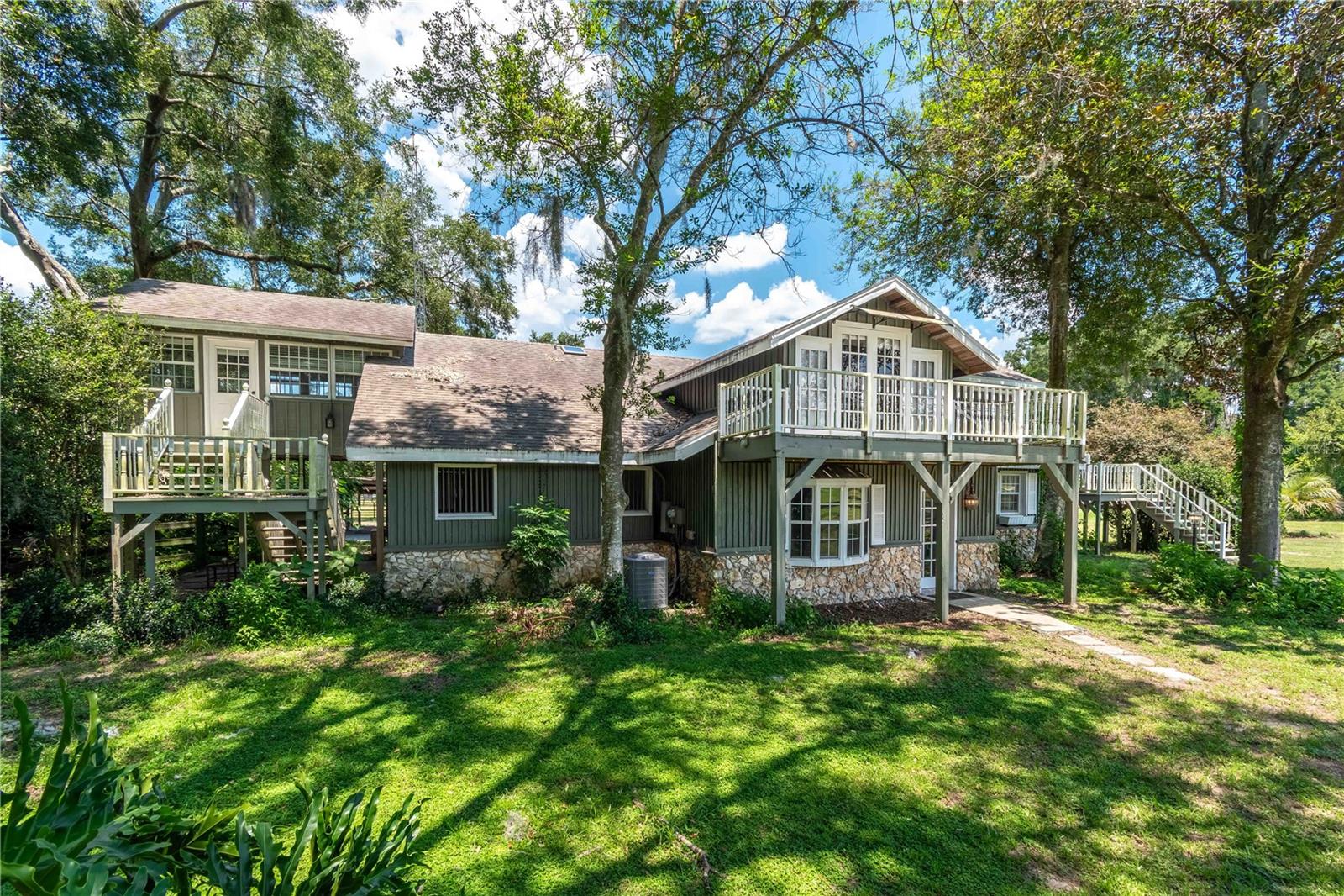 Set on 5.59 acres within Ocala’s desirable equestrian community of The Meadowlands, this thoughtfully designed estate balances high-level functionality with understated elegance. Created with equestrians in mind, the property features two barns offering a total of 10 stalls, each featuring matted floors, concrete aisles, hot and cold wash areas, and covered run-ins. Five manicured paddocks, two large pastures, a trailer shed, and dedicated hay and shavings storage provide seamless daily operations. A well-appointed tack room includes a full bath, kitchenette, and laundry. For year-round training, the newly built 120’ x 200’ irrigated GGT arena, completed in 2024, offers year-round training options. The Meadowlands also allows for effortless riding both on and off property. At the heart of the property is a distinctive two-story, two-bedroom barndominium-style residence, constructed with structural steel, concrete block, and rich wood beams. The upper-level owner's loft includes one-bedroom and one-bath, with warm pine floors, French doors throughout, and a wraparound porch ideal for capturing views of the farm. The gourmet kitchen features Carrara marble countertops, an Italian apron-front sink, and a full suite of high-end appliances. Below, the attached one-bedroom apartment includes a private entrance, full bath, kitchenette, and screened porch, offering ideal accommodations for guests, extended stays, or rental income. The second residence is a lovely 2-bedroom, 1-bath cottage which is fully furnished and provides additional versatility with an open living area, updated kitchen, and a charming screened-in porch overlooking the pastures. Outdoor enhancements include a private shower, washer and dryer, and a dedicated grilling area, all designed for comfort and convenience. Whether used as a primary residence, guest cottage, caretaker quarters, or a high-demand AirBnB rental, the space offers exceptional flexibility. A workshop, RV pad with full hookups, and a 2024-compliant septic system complete the farm’s operational offerings. The estate is graced by curated views, lush grounds, and gentle shade from mature trees, an ideal landscape for equines and riders alike. All of this is ideally located just 20 minutes from Downtown Ocala, 20 minutes from both the World Equestrian Center and HITS, and 35 minutes from Gainesville. Offering a rare blend of natural beauty, modern infrastructure, and income-generating potential, this exceptional farm is perfectly suited for the equestrian lifestyle.