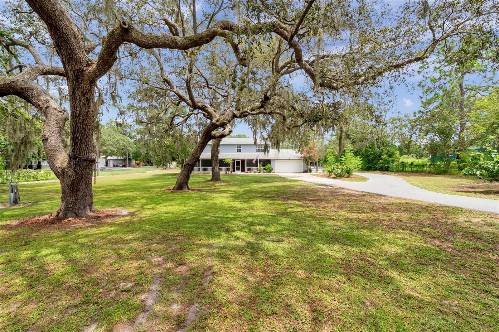 Nestled on a sprawling 1+ acre parcel this inviting two-story home blends rural charm with modern comfort—perfect for anyone dreaming of a hobby farm lifestyle. Surrounded by mature trees and open sky, the property offers ample space for gardens, animals, and outdoor projects.
The main level of the home features a welcoming wrap around screened covered porch, ideal for enjoying morning coffee. Inside, you'll find spacious rooms perfect for every day living or entertaining. A country-style kitchen boasts ample cabinetry, stainless steel appliances, and a cozy breakfast nook overlooking the backyard. There's also a mudroom/laundry combo—perfect for kicking off boots after a day outdoors.
Of the 5 bedrooms, there is a primary bedroom with an ensuite on both the main floor and on the 2nd floor. The other 3 bedrooms are upstairs.
You'll enjoy the above ground pool in the backyard to cool off and relax. The pool was installed in 2019. Screened lanai at the back of the house overlooks the amazing backyard and pool.
2 car garage plus a detached 14x16 shed and a pole barn with 3 stalls.
Roof new in 2018. HVAC - upstairs unit installed in 2015 and downstairs unit installed in 2024. Water heater installed in 2018.
Orchard on the property has: fig, loquat, lemon, mandarin, moranga, and mulberry trees.
"Zero turn" riding lawn mower will stay with the property.
