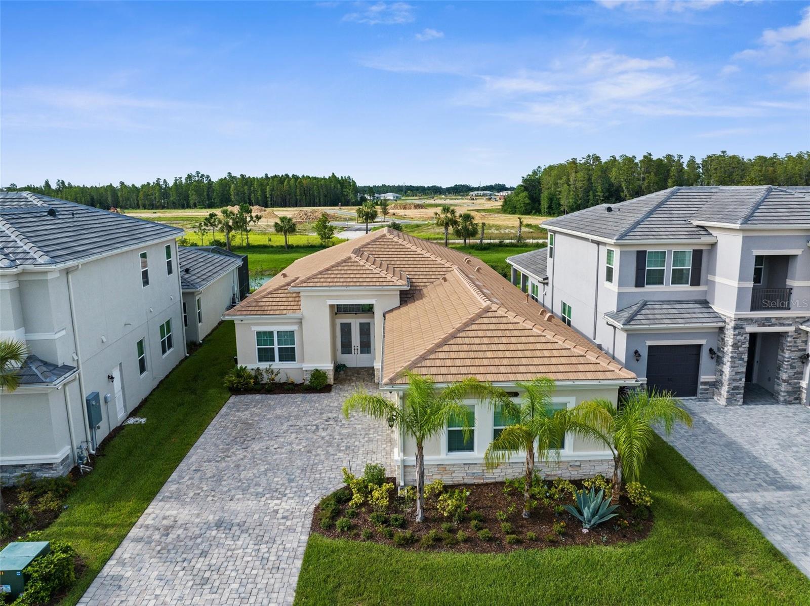 Welcome to 32309 Rosewood Meadow Ln, an impeccably maintained 2023-built GL Homes residence in the prestigious Winding Ridge community of Wesley Chapel. With 2,424 square feet of thoughtfully designed living space, this one-story home offers the ideal blend of elegance, comfort, and privacy—all on a premium conservation lot with serene pond views. The extended pavered driveway, tile roof, and lush landscaping create a sophisticated first impression. Inside, you'll find marble-look tile flooring throughout, sleek modern fixtures, and a designer kitchen featuring quartz countertops, built-in double ovens, a spacious island, and crisp white shaker cabinetry. The open-concept layout flows effortlessly through the dining and living areas, framed by tray ceilings and expansive windows that bring in natural light. The private primary suite includes twin walk-in closets and a spa-like bath with dual vanities, soaking tub, and glass-enclosed shower. With 3 spacious bedrooms, 2.5 baths, a separate office/den, and a large covered patio overlooking the treeline, the home offers both functionality and timeless style—with space to add your dream pool. Impact windows and doors, modern upgrades, and like-new condition throughout make this a true turnkey opportunity. Enjoy luxury living with resort-style amenities including a clubhouse, fitness center, pickleball, tennis, basketball, splash zone, playground, and more. HOA includes full lawn care. Just minutes to top-rated schools, Wiregrass Mall, Tampa Premium Outlets, hospitals, and dining.
