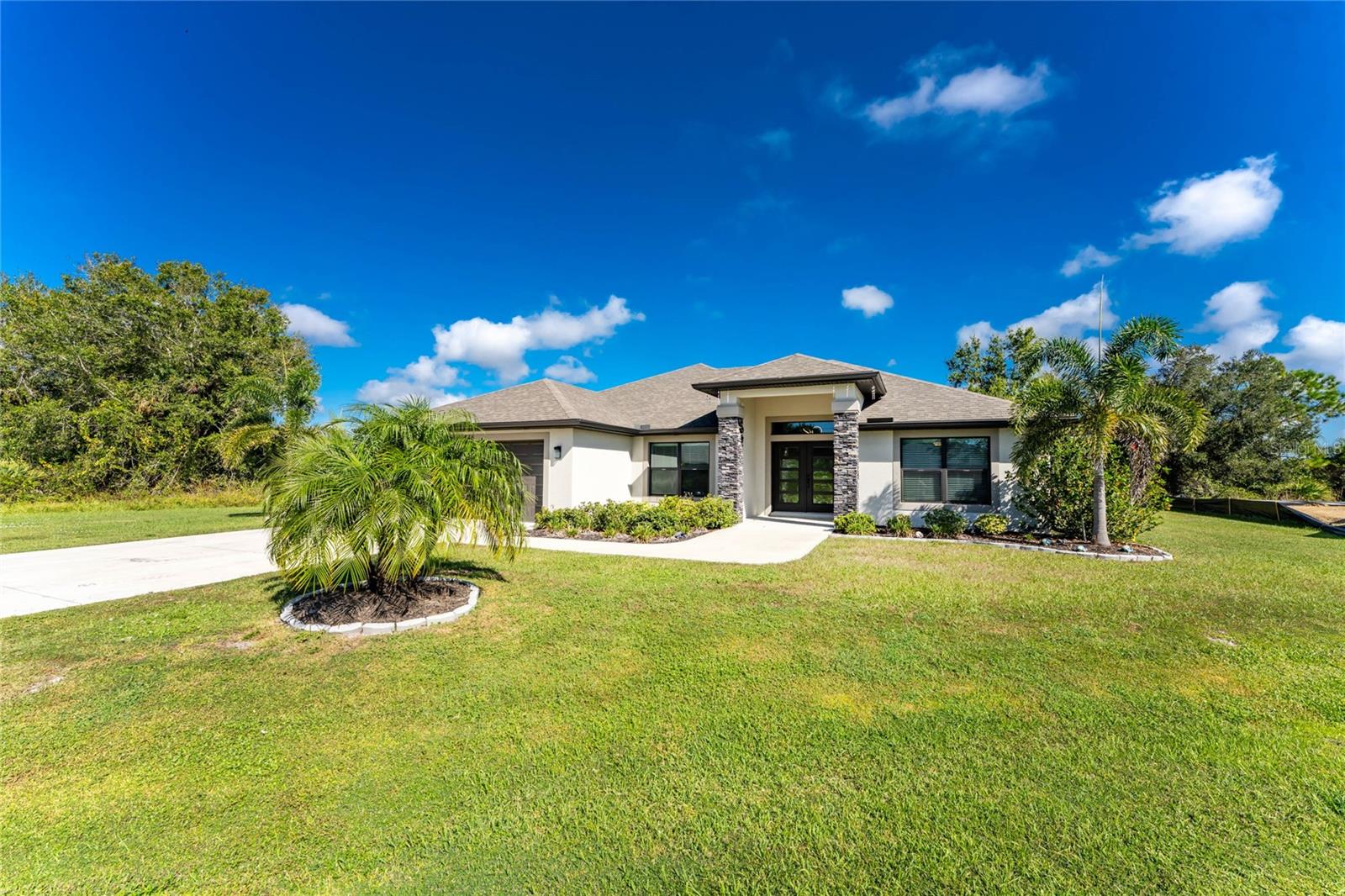 Built in 2022, stroll into this stunning home from the wide front side walk and large covered front entry which offers the charm of brand-new construction while being perfectly tucked away at the end of a cul-de-sac in the highly sought-after Deep Creek community. With over 1,800 square feet of living space, there’s plenty of room to entertain family and friends in style.  Elegant custom finishes are found throughout — including custom impact rated 5 panel glass double main entry doors, trey ceilings, hard-surface countertops, tile flooring, and custom lighting — setting this home apart from others on the market. Laundry room access through to the garage features stainless feel front loading washer and dryer both on pedestal drawers for added storage plus sink and cabinetry features.  Enjoy the spacious layout featuring a separate den with French glass doors, high ceilings, with a BUYER BONUS of multiple large flat-screen TVs with mounts already in place, perfect for Sunday night football.  The master suite offers dual walk-in closets, dual sinks, a luxurious walk-in shower, and private access to the screened lanai. The split-bedroom floor plan provides privacy and functionality, complemented by an open kitchen and great room. The kitchen features a large eat-in island, separate dining area, pantry, stainless steel appliances, and abundant cabinet space.  The air-conditioned two-car garage with epoxy flooring is ideal for keeping your vintage car or prized possessions protected from the Florida heat.  Deep Creek is a deed-restricted community with low annual HOA dues of just $200 and access to exceptional amenities — including a community park, sidewalks, tennis and pickleball courts, basketball court, playground, and a scenic golf course — perfect for an active lifestyle. Conveniently located near I-75, Walmart, Publix, shopping, dining, and medical centers, plus beautiful Florida beaches are not but a quick drive away.