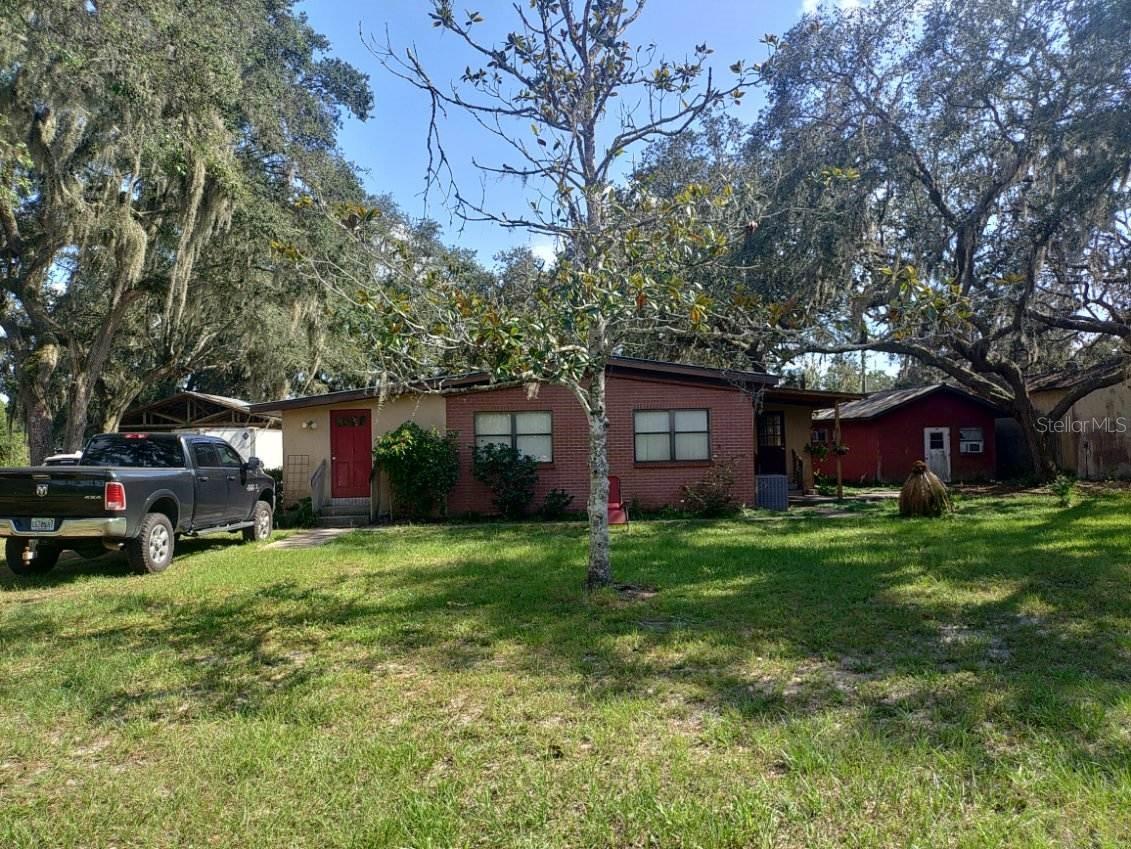 This small property has so many big things for the potential buyer. Originally a single wide mobile home, now with two spacious additions, sitting under beautiful old oaks at the end of the road. Truly, at the end of the dirt road. A large living space, kitchen open to small dining area, and currently two bedrooms, which was originally three but can be reverted back to three. Outside there is a 24x36 frame and stucco workshop, wired for 220, with two open bays at each end, and an enclosed area that could serve as an office or extra storage. There is an additional frame and stucco building that could serve as storage. The property is adjacent to a large privately owned wooded tract, distant neighbors, quiet and peaceful. Perfect for the seasonal owner who needs RV or trailer storage; perfect for the auto mechanic guy who needs a great garage/workshop; perfect for the home-schooler who could use the additional buildings for classrooms. So many uses on the small property. So much usable space on this sweet property! It is well worth the look!