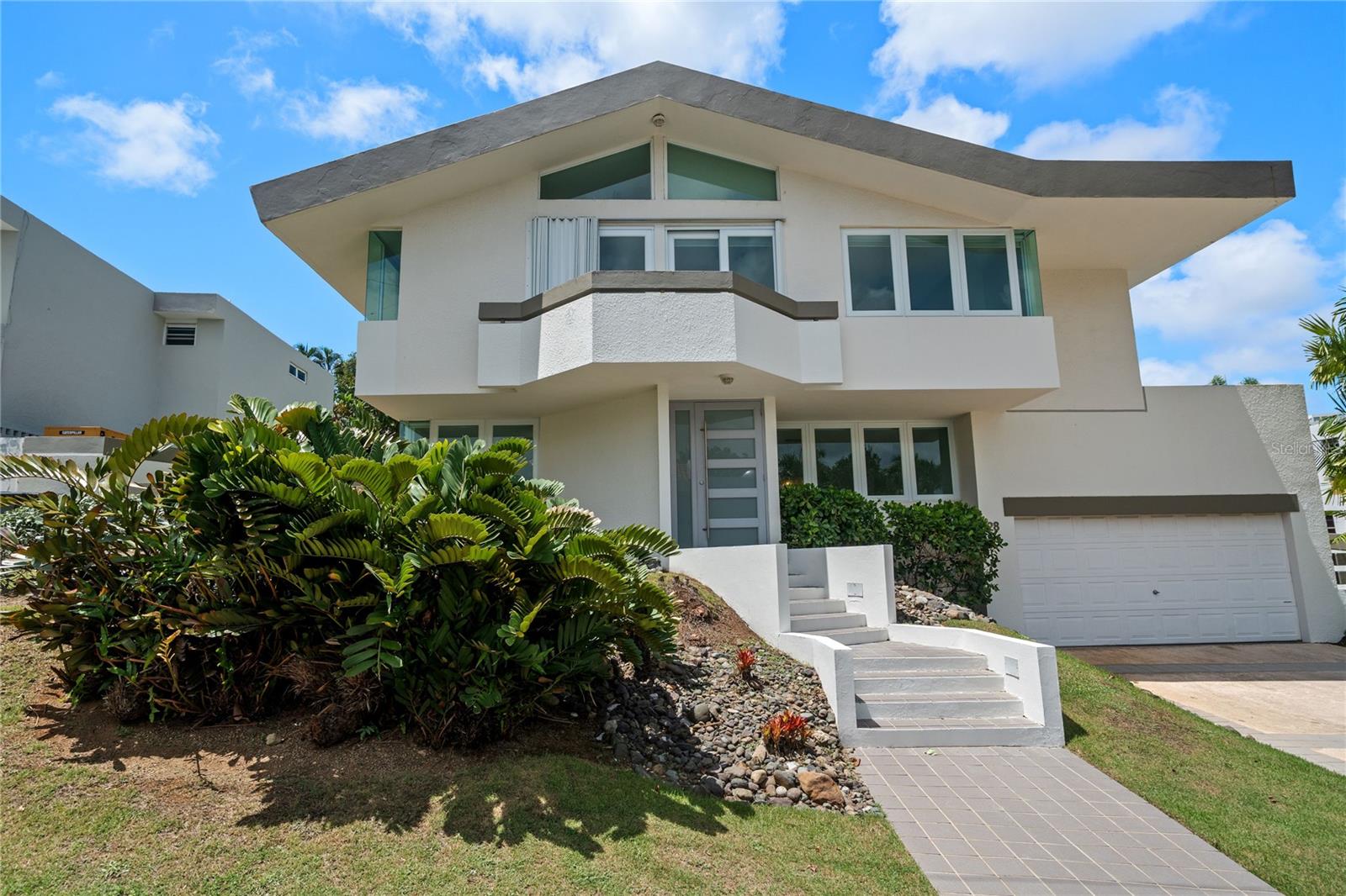 Welcome to B-28 at Baldwin Park, a remarkable property nestled in the heart of Guaynabo. This expansive 4,565 square-foot residence with a 981.37 square meter lot offers a harmonious blend of comfort and functionality, making it an ideal choice for families seeking a suburban lifestyle in a vibrant community.
Upon entering, you are greeted by an open space, cathedral ceilings and bright natural light - seamlessly connecting the living, dining, family, and kitchen areas – creating an inviting atmosphere for both everyday living and entertaining. The well-appointed windowed kitchen is designed to cater to culinary enthusiasts, with a handsome quartz countertop island and modern subway tile backsplash, this chef’s kitchen provides ample space for meal preparation and gatherings. This home boasts 4 bedrooms on the second level and a convenient 5th ensuite bedroom on the main floor. The primary suite offers a flex area or bonus room, serving as a potential gym, media room, or home office, tailoring it to your lifestyle needs and enhancing the property’s adaptability. The residence features 3 full bathrooms and 1 half bathroom. Primary bathroom has a newly renovated double vanity and double shower. Modern fixtures and finishes throughout the home underscore its commitment to quality and well-being.
Step outside to discover the best of the home - a serene backyard oasis, perfect for relaxation and recreation. The inviting pool and jacuzzi is the centerpiece of this grand, expansive and private outdoor space. The backyard’s layout is perfect for outdoor activities, gardening, or simply unwinding in a tranquil setting surrounded by a matured verdant landscape. This remarkable opportunity offers the quintessential suburban lifestyle in one of the most sought-after neighborhoods in Guaynabo, across the street from Baldwin School - ranked amongst the best on the island. This gated community with 24/7 security, is home to just 38 residents and is highly regarded for its welcoming atmosphere. It’s proximity to essential amenities, including parks, shopping centers, and dining options makes this unique offering highly desirable.
With its impressive square footage, thoughtful design, and desirable location, B-28 at Baldwin Park is poised to meet the needs of discerning buyers looking for a family-friendly environment with modern conveniences.
Schedule a viewing today to experience firsthand the unique features and potential this property holds.
