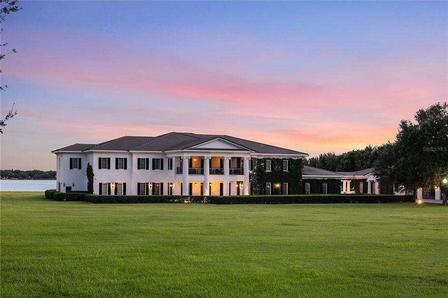 Showcasing Central Florida’s most iconic lakefront estate: an 18-acre compound with 614 feet of pristine frontage on Lake Down on The Butler Chain of Lakes. The Windy Ridge Estate is comprised of multiple buildings spanning 51,000 square feet of space including an expansive 20,333 square-foot Georgian-style Plantation mansion that is a showplace residence with generous luxurious spaces, classic elegance, and the ultimate in security and serenity. The walled entry opens to a grand foyer with a floating mahogany staircase, marble floors, paneled walls, and Murano chandeliers. An art gallery leads to a spacious living room featuring rich mahogany millwork and expansive lake vistas. Gourmet kitchen: salamander, dual double convection ovens, commercial icemaker, full-size refrigerator, and freezer. The main level includes one of two owners' suites, plus a library-lounge or a possible sixth bedroom. Dual staircases or a Thyssenkrupp elevator provide access to the upper level, which features four-bedroom suites, including the primary retreat. An 85-foot parlor with 20-foot ceilings, built-in bookshelves, and a wet bar provide a dramatic entertaining space. Screened porch captures southern lake views and Disney fireworks. Breezeway connects to a 5,600 SF rustic lodge with a bar, catering kitchen, entertainment hall, and locker facilities. Outdoor amenities: Junior Olympic pool, spa, decorative fountain, architectural lighting, direct lake access. The vast and open water location offers an ideal space for seaplane arrivals and departures. Additional structures include a 4,000 SF paneled garage with 20-foot ceilings, an office, and a guest apartment; a 3,800 SF storage building; three separate garages accommodating motor coach and car collection; and staff quarters with a private courtyard. A rare fusion of Southern grandeur, lakefront serenity, and equestrian potential—without any interference of an HOA.  Truly a legacy compound crafted for those who demand the extraordinary.