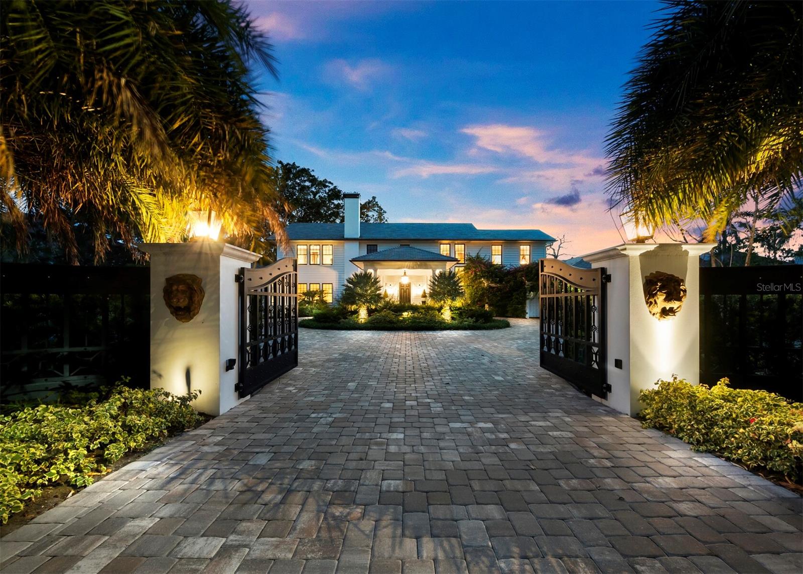 Situated on a superbly landscaped 1.58-acre lot with over 200 feet of bay frontage, this 5,700-square-foot home in sought-after Indian Beach/Sapphire Shores was meticulously reimagined while retaining its historic charm during a three-year renovation completed in 2020 by builder Bruce Saba. Originally built in 1940, the two-story 4-bedroom, 5.5-bathroom home boasts sweeping views of Sarasota Bay, sturdy Hardie plank lap siding, a durable recycled rubber roof, hurricane impact windows & glass doors, & steel gutters. A white wall with a private entry gate welcomes visitors to the estate’s expansive paver motor court & porte cochere, providing convenient access to the front entry with an ornate door knocker. Large windows & French doors throughout the residence showcase scenic bay views, captivating gardens, manicured landscaping & mature trees, including a massive ficus tree in the backyard. The thoughtfully curated interior features walnut flooring, exquisite millwork, 12-inch baseboards, stunning lighting fixtures & distinctive décor. Six accordion glass doors in the voluminous formal living room/dining room open to a long covered bayfront terrace & spacious open patio overlooking the sprawling backyard, bay & Longboat Key. Adjacent to the terrace is a sleek tiled pool & spa with a waterfall & outdoor bathroom. The enormous outdoor living space is ideal for entertaining, family activities, pets & viewing sunsets along a pathway beside a small sandy beach & the water. French doors from the patio & pool offer access to a zebra-themed room, which could be used as a pool cabana, den, or formal dining room, & a dazzling kitchen with marble countertops & island/breakfast bar, abundant white cabinetry, eight-burner Wolf range, Wolf convection oven & separate paneled Sub-Zero refrigerator, freezer, & wine cooler. The kitchen also has eye-catching antique wooden doors for separation from the dining area if desired. The main level also has a family room with a striking stone fireplace and wood, glass & wrought-iron sliding doors to a spacious office/study with a full marble bathroom that could serve as a fourth bedroom. Take the elevator or curved walnut staircase with wrought-iron handrails to the second level, featuring an en-suite guest bedroom with large windows facing the bay and front yard & two primary suites with electric shades, custom walk-in closets with built-ins & French doors to a screened bayfront balcony. Both primary bathrooms include marble counters, herringbone tile, sizable vanities, walk-in marble showers and oversized windows. One bathroom has a separate soaking tub while the other is pre-plumbed for a tub. The residence is surrounded by picturesque tropical landscaping, including a koi pond in the front yard with mango, banana & star fruit trees, and a Ylang-Ylang tree with fragrant flowers that are used to make Chanel’s classic perfume. The original two-car garage with a bathroom sits on the south side of the property, where traveler’s palms were added for additional privacy. Other notable highlights include ceiling fans on the terrace and balconies, landscape lighting, three-car air-conditioned garage with washer and dryer, second-level laundry room, tankless water heaters, two 2023 AC units & original attic with storage. This remarkable waterfront estate is less than a mile south of The Ringling Museum, about 1½ miles to Sarasota airport & a short drive to downtown Sarasota’s abundant dining, shopping and cultural arts.