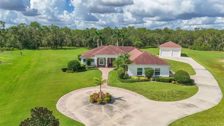 Escape to your own private Florida oasis in the desirable Foxbrook community of Parrish. Tucked at the end of a peaceful, no-through-traffic cul-de-sac, this custom-built 2014 Florida ranch-style home by Johnson Homes blends open-concept living, modern updates, and expansive space on 5 beautifully landscaped acres—half manicured and half wooded for your perfect retreat and playground.

Inside, you'll find 4 generous bedrooms, 3 full baths, a dedicated office, separate laundry room, and spacious walk-in pantry. The bright, open layout boasts real tile floors, an updated kitchen with granite countertops, two sinks (one in the island), stainless appliances, and mini fridge. The living room features an electric fireplace and opens directly to the pool through 11-ft three-panel sliders for effortless indoor-outdoor living. The primary suite includes his-and-hers closets and a luxurious en-suite bathroom. Impact-resistant doors and windows provide hurricane security (no shutters needed), with fresh paint throughout for true move-in readiness.

Energy efficiency stands out with high-quality spray foam insulation in the home's attic and the outbuilding's walls and attic—keeping electric bills remarkably low even in Florida's heat.

The real highlight is the over 2,500+ sq ft of climate-controlled garage space: an oversized attached 2-car garage (AC'd and tall enough for a boat or small RV) plus a massive 2024-built detached outbuilding/garage—ideal for cars, RVs, boats, motorcycles, hobbies, or storage. Two car lifts stay with the right buyer, saying goodbye to off-site storage fees. A true gearhead's dream!

Your resort-style backyard includes a private saltwater pool (remodeled 2023) with jacuzzi, full outdoor kitchen (grill, sink, mini fridge, cabinets, wood ceilings, fans), uplighting, 2024 hardscaping, multi-zone sprinkler, and bug system. Towering royal palms, woodland paths for off-road fun, and a hardscape patio perfect for fire-pit evenings—all with complete privacy!

Curb appeal impresses with a large circular driveway for easy guest access and parking, plus a spacious private drive.

Foxbrook offers a friendly, family-oriented vibe with low quarterly HOA fees (covering maintenance and roads, no CDD). Amenities feature a playground with pavilion, basketball/soccer fields, bike paths, and nature trails. Enjoy year-round events like golf cart parades, Easter hunts, Halloween trunk-or-treats, and weekly food trucks. It's safe, walkable, bike- and golf-cart-friendly, with abundant wildlife and caring neighbors.

Conveniently located near top schools, shopping, the new Parrish Community Park (opened 2025 with playgrounds, splash pad, trails, amphitheater, and shelters), Lakewood Ranch, Gulf beaches, and quick drives to Tampa (~40 min), St. Pete, and Sarasota.

This rare, turn-key gem is perfect for boat/RV enthusiasts, car collectors, or anyone craving space, privacy, efficiency, and the best of Florida living.  Schedule your private tour today. Properties like this move fast!