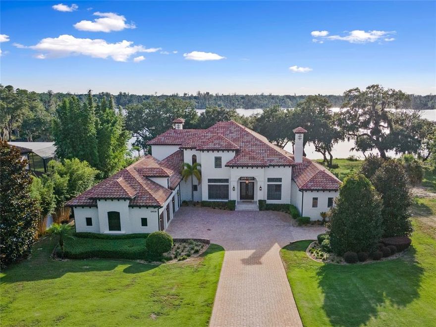 Exquisite custom home directly on the Clermont Chain of Lakes with spectacular and brilliant Florida sunsets. Live vacation life every day on the lakes, in the pool, or enjoy all this home has to offer inside and out. Expertly laid out design with the master suite, family and formal rooms on the main level, additional bedrooms and family areas upstairs and an amazing lower level with secondary master suite, kitchen, game room and family room areas for the ultimate in entertaining. Arrive at the home through the electric gates and down the paver driveway to the front entry where you are greeted by massive custom front doors leading you into this masterpiece. Your eyes are drawn through the wall of windows out onto the diamond shimmering lake. The formal living room is one vantage point in this house with those incredible views. Sliding glass doors from the family room lead you out onto the wide, covered balcony overlooking the massive pool, spa, dock and lake. The gorgeous kitchen has tons of granite countertops, custom cabinetry, top-of-the-line appliances and a breakfast nook with seamless windows is afforded the same views. The luxurious master suite is on this main level, has a phenomenal walk-in closet and huge bath. A dedicated office with classic cabinetry and shelving is ready for you to get back to work, and what a great location in sunny Central Florida to do so! One set of stairs off the butler's pantry area leads you up into a 27-by-13-foot bonus room with half bath, perfect for a home theater, studio or additional office space. The other staircase leads you up to three additional bedrooms (two en suite and one with a bath shared with the second family/game room). Down to the lower level, there is a fully equipped kitchen with range, dishwasher, refrigerator, a full bar with raised countertops, a dining room, living room, family room and secondary master suite, all with views of the pool and lake, accessible through the sliding glass doors. Entertaining for dozens of people is entirely possible in this area alone. Parties of 100 would not be difficult! Want more peace? Relax by the pool - sit in chairs with your feet in the water, move to the spa or float in the beautiful water. In the evening, the pool and outdoor lighting transforms into a resort feeling under the stars. The summer kitchen is fully equipped with a refrigerator, grill and sink. Follow the pavers to the fire pit under the gorgeous old oaks framing the rear of the home. Meander to the dock, fish from the deck or ascend to the second level of the dock for optimal views of those famous sunsets. Jump on a boat, kayak or canoe and explore all that Clermont has to offer. Take an adventure down the crooked river to Lake Louisa and stop by the state park or take the boat to Lake Minneola where you can grab a beverage or meal at the tiki bar or downtown Clermont with all the revitalized areas here and coming! This is truly an incredible home with almost 7,500 square feet of living area, oversized three-car garage, tiled roof and everything that comes under it! Please see the interior/drone video and make your appointment today for your forever home!