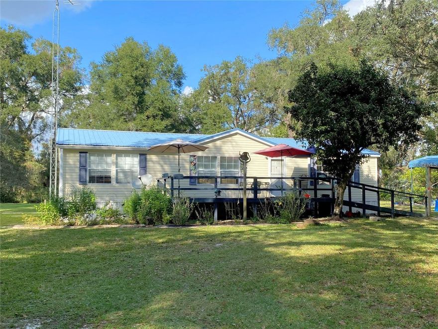 Great Property - Tucked away just minutes from town, this privately situated 7± acre property is full of surprises. The home features a metal roof, generous living spaces, and an oversized kitchen with abundant cabinetry, a breakfast bar, and an easy connection to the dining room. The spacious primary bedroom offers a large walk-in closet and a roomy bath with newer flooring, a 2023 commode, double vanity, garden tub, and walk-in shower.

Outdoors, the land blooms with personality: Meyer lemon, pink grapefruit, orange, peach, mulberry, fig, avocado, and grapefruit trees, plus blueberries and grapevines. A fenced garden area awaits your green thumb, complete with a 12x24 covered sitting area where you can relax and enjoy the literal fruits of your labor.

Additional property features include a 12x24 storage building with electricity, an RV carport, and a massive 40x60 metal building at the front of the property that contains two shipping containers—ideal for extensive storage. A separate pole barn sits alongside it for even more space.

Other perks: an on-demand tankless water heater, included washer and dryer, multiple exterior water spigots, and a serene setting at the end of a dead-end road. Close the gate, inhale the quiet, and let the world fade away.