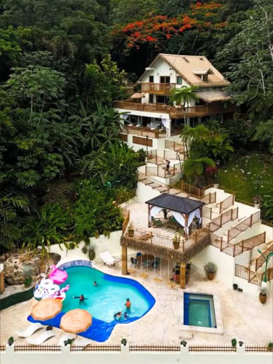 Experience the magic of Casa Bali, a luxurious 5-bedroom, 6-bath residence nestled within the lush El Yunque Rainforest. Perfectly situated on a quiet cul-de-sac for maximum privacy, this tropical sanctuary offers two pools, expansive open-concept living areas, and breathtaking ocean and rainforest views from the upper balcony. Each bedroom features its own ensuite bathroom, blending comfort and sophistication. A serene waterfall behind the home fills the air with the soothing sounds of nature and flowing water. The property includes a full backup generator and is currently rented long-term until 2027, with the lease to be honored by the new owner. Surrounded by nature yet designed for modern living, Casa Bali is a true paradise retreat. Schedule your private viewing today!..