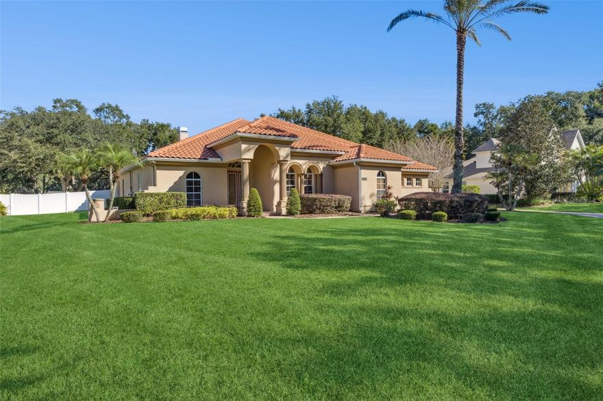 Tucked within the gates of Regal Point, one of Kissimmee’s most enchanting enclaves along the shores of Lake Toho, this custom-built residence blends timeless craftsmanship with modern comfort. Set on nearly an acre along brick-lined streets shaded by majestic oaks, the home welcomes you with a long paver driveway, lush landscaping, and a graceful tile roof. Inside, natural light fills a flowing design that includes a flex room with in-ceiling speakers, a private office with double doors, elegant formal dining, and a warm living area featuring built-in surround sound and a cozy gas fireplace. The kitchen pairs function and beauty with rich cabinetry, stone counters, and a sunny breakfast nook overlooking the extended screened lanai, where a fully equipped summer kitchen with grill, sink, ice maker, and beverage fridge invites effortless entertaining. The split-bedroom layout ensures privacy, placing the primary suite apart from the secondary bedrooms, and offers in-ceiling speakers in the primary bath for a spa-like experience. Outdoors, the front landscaping glows with accent lighting, while the fenced backyard features solar illumination and a paver fire pit platform for evening gatherings. Smart-home upgrades include three Ring doorbell cameras, a lanai camera, and a MyQ garage door system. The three-car side-entry garage showcases a durable Polyaspartic floor finish, and comfort throughout the home is enhanced by two recently replaced A/C units (2022 and 2025). Regal Point is a gated lakeside community where homes rarely come available—celebrated for its beauty, privacy, and enduring appeal.