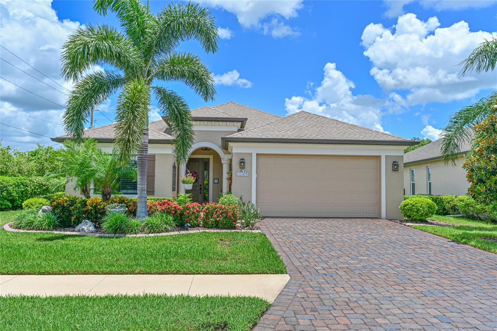 Impeccably Maintained Home in the Gated Community of Greyhawk Landing. Enjoy serene lake views and a lifestyle of comfort in this beautifully cared-for home, set on a premium lot with manicured landscaping and a paver driveway. Inside, a welcoming foyer greets you with warm wood-look plank tile flooring and 8’ doors, setting the tone for the stylish touches found throughout. This thoughtfully designed 2-bedroom, 2-bath home includes a versatile den or home office, perfect for today’s flexible living needs. The popular great room floor plan features a spacious living area with a tray ceiling accented by decorative wood beams and crown molding throughout the entire home, creating an elegant ambiance. The chef’s kitchen is both functional and modern, equipped with stainless steel appliances, granite countertops, gas stove, under-cabinet lighting, a double garbage pull-out, tile backsplash and a stylish Café refrigerator. Upper and lower cabinet crown molding and a closet pantry complete the space with efficiency and style. The spacious primary suite features luxury vinyl flooring, a tray ceiling, plantation shutters, and a generous walk-in closet. The ensuite bath is beautifully upgraded with quartz countertops, dual sinks, modern lighting and faucets, a tiled-to-ceiling walk-in shower, and plantation shutters. Enjoy the Florida lifestyle on the covered screened, paver lanai or relax under the modern pergola overlooking the tranquil lake. The split floor plan offers privacy for guests or family members, with a secondary bedroom and bath located at the front of the home. Additional highlights include: Whole-house water filtration system, Plantation shutters throughout, dedicated laundry room with front-load washer and dryer, sink, and cabinetry, mudroom entry from the garage with barn wood bench and storage, gutters, curbed landscaping, two-car garage with overhead hanging storage and included hurricane shutters. Residents have access to exceptional community amenities. Featuring 2 resort-style pools, 2 Community centers, Playgrounds, fitness center, Tennis, pickleball and basketball courts, soccer and baseball fields, bass-stocked lakes, and miles of nature trails. Situated in the heart of Sarasota/Bradenton with close proximity to world-renowned Beaches, and great shopping and dining at UTC Mall. Easy commute to Sarasota and Tampa airports. This home combines elegant upgrades with practical features in one of the area’s most desirable gated communities.