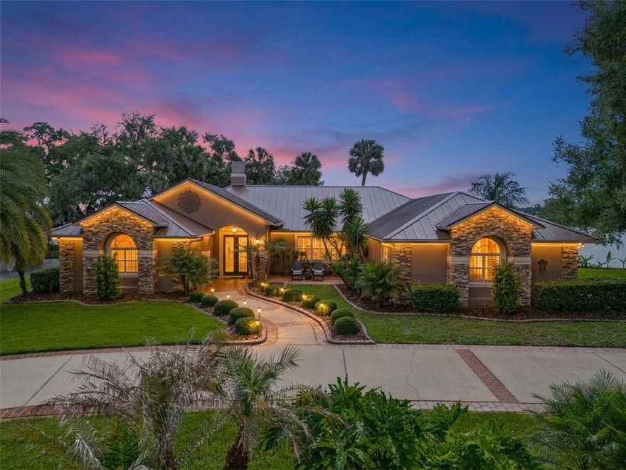 Imagine waking up every morning to breathtaking sunrise views over LAKE DORA, one of the crown jewels of the renowned Harris Chain of Lakes. This exceptional lakefront estate offers the ultimate Florida waterfront lifestyle on a rare 1-acre double lot boasting an impressive 305 ft of solid CONCRETE SEAWALL, a feature seldom found and highly coveted for its unmatched water frontage and stability. Completely renovated in 2020, this 3-bedroom, 2 1/2-bathroom home welcomes you through elegant double front doors into an expansive, light-filled open-concept living area. Towering windows and strategic design ensure PANORAMIC LAKE VIEWS from every room in the house. A wood-burning fireplace serves as the heart of the living room. The gourmet kitchen is a true showstopper, featuring quartz countertops, a massive island with abundant seating and prep space, new Thermador appliances and seamless flow into the living area. A custom-built bench seat nestled beneath a large picture window invites you to sit and soak in the serene lake views while enjoying a morning coffee or entertaining guests. Pocket sliding glass doors disappear completely, blurring the lines between indoor and outdoor living as they open wide to the resort-style backyard. One bedroom was masterfully reimagined as a sophisticated wet bar, complete with a huge picture window framing the sparkling lake, an ideal spot to craft cocktails while watching the sunset or hosting unforgettable parties. The spacious primary suite offers a private sanctuary with generous room for a king-sized bed and sitting area. It features direct access to the pool patio with pocket sliding doors overlooking the pool and lake. The exquisite master bathroom is a SPA-LIKE RETREAT with luxurious finishes, designed for ultimate relaxation with a skylight that provides optimum natural lighting.  The additional bedroom provides flexible space for family, guests, or a home office. The large screened enclosure protects a sparkling SPOOL, an integrated pool + spa combination, a 4’ Waterfall, and an 18-FT ELECTRIC RETRACTABLE SCREEN allows you to open the space completely on perfect Florida days. The expansive pool deck offers ample room for sunbathing, dining, and large-scale entertaining. A fully equipped summer kitchen makes outdoor hosting effortless and a MOSQUITO NIX SYSTEM helps keep pests away. Both front and back porches feature upgraded Tongue and Groove ceilings. Additional outdoor highlights include a tranquil POND WITH 2 FOUNTAINS, plus a FOUNTAIN IN THE LAKE along the seawall. Permanent exterior GOVEE lighting illuminates the property beautifully after dark, there is a PRIVATE DOCK complete with boathouse and boat lift, both the main house and boathouse have BRAND NEW METAL ROOFS for lasting peace of mind, convenient 50-amp RV hook-up for visiting family or friends and a circle driveway and mature landscaping enhance superb appeal. With Plantation Shutters and crown molding throughout, premium finishes, whole house generator and thoughtful details at every turn, this home delivers both everyday luxury and exceptional entertaining capabilities. Expansion Opportunity: The current owners have professional plans drawn up to convert the existing garage into two additional bedrooms plus a Jack-and-Jill bathroom, while constructing a new two-car garage. The Harris Chain of Lakes is famous for its world-class fishing, scenic boating routes, waterfront restaurants and bars, and even seaplane access.