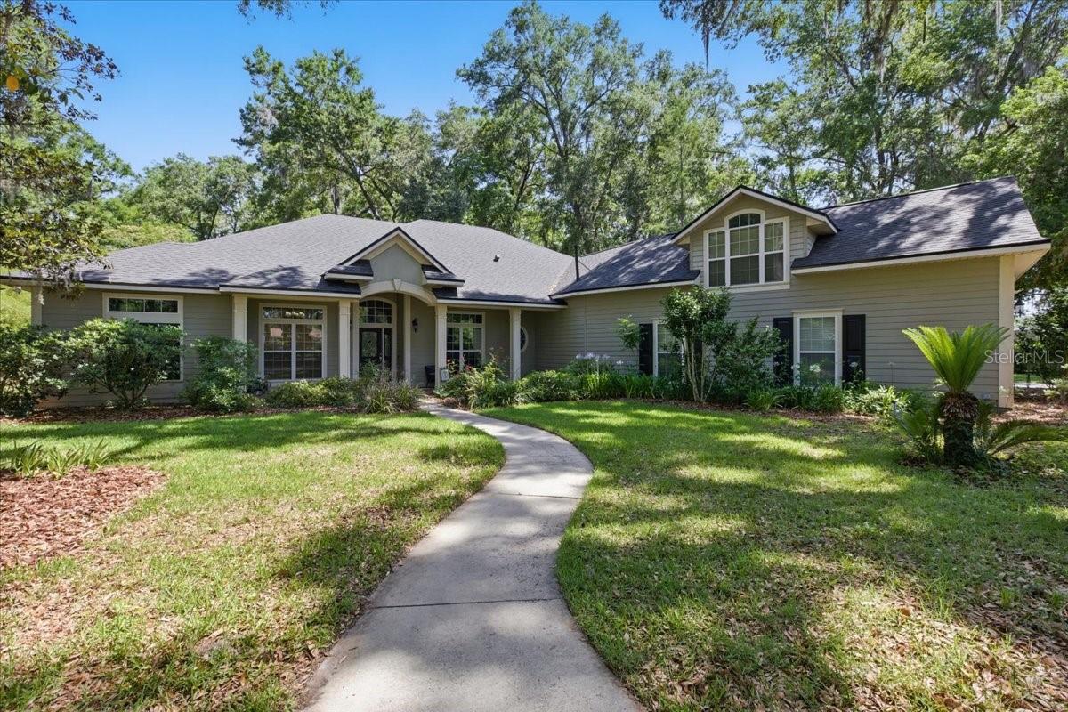 Gated estate with acreage, pool, and unmatched flexibility.
Welcome to Steeplechase Farms, a premier gated community just west of Gainesville, where peace, space, and privacy converge. This custom-built estate home sits on 1.78 oak-shaded acres and offers over 4,100 square feet of living space designed for both comfortable everyday living and gracious entertaining.
Tucked behind a private gate, the circular driveway leads to a stately brick façade and oversized 3-car garage with generous storage and workbench space. Step inside to discover soaring vaulted ceilings, a dramatic floor-to-ceiling stone fireplace, solid wood cabinetry, and expansive living areas with natural light filtering through large windows.
The 5-bedroom, 3 full and 2 half bath layout includes a thoughtfully designed split plan and a spacious upstairs bonus room with its own half bath—ideal for guests, a media room, home office, or creative studio. The open kitchen connects to both formal and casual dining areas, creating a natural gathering space for everyday life or entertaining. The owner’s suite opens directly to the pool area and includes dual closets, a walk-in shower, garden tub, and private water closet.
Step outside to your own private retreat—a lagoon-style screened pool with rock waterfall, covered lanai, and plenty of space to relax or entertain beneath a canopy of mature trees. Behind the home, the back portion of the acreage has been thoughtfully left in a natural state with walking paths cut through the trees—ideal for morning strolls, birdwatching, or enjoying the quiet beauty of native Florida landscape. There’s also ample room for gardening, pets, or outdoor enhancements like a firepit or play area.
Practical features include a separate laundry room with utility sink and additional storage throughout. Key system updates include a brand-new architectural shingle roof (2024), newer HVAC system (2021), and propane water heater (2020). While some finishes reflect earlier design choices, the home is move-in ready and priced with room to personalize. Seller is open to offering a closing credit for flooring, paint, or countertops with acceptable terms.
Enjoy community amenities including a two-mile riding trail, estate-sized lots, and a tranquil setting—all just minutes from shopping, UF Health, the University of Florida, and top-rated schools.
Schedule your private tour today and experience the possibilities of this exceptional North Florida estate.