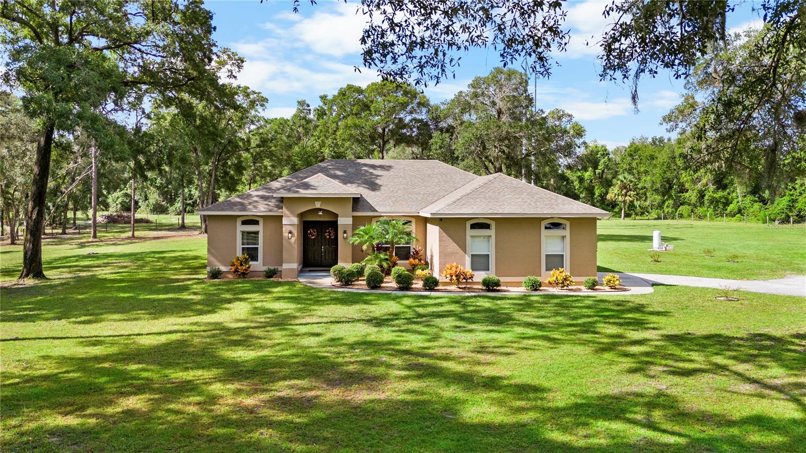 One or more photo(s) has been virtually staged. IMMACULATE! IMPECABLE! REALLY ALMOST TOO GOOD TO BE TRUE! EVERYTHING about this sweet little gem TICKS ALL THE BOXES!
LOCATION, SETTING & EXPANSIVE ACREAGE–Tucked among some of DeLand’s most distinguished estates, this 2.5-ACRE ESTATE combines privacy, freedom, & natural beauty, all just 10 minutes from I-4. A turn onto Pressly Circle reveals a winding road beneath a canopy of majestic oaks, ending in a peaceful cul-de-sac where this inviting charmer proudly graces. Beyond the electronic GATE lies a property CLEARED & FULLY FENCED! With NO HOA & the flexibility of UNINCORPORATED VOLUSIA COUNTY, the possibilities abound! Zoned RES/AG, the estate welcomes HORSES! The grounds are further enhanced w/an IRRIGATION SYSTEM, covering the perimeter of the lush grassy yard.
HOME–Two upgraded LANTERNS flank the covered entry, framing the 8’ DOUBLE FRONT DOORS that open into a living space where 10’ CEILINGS soar & NEW LUXURY VINYL WOOD PLANK FLOORS extend—working in harmony to create a warm & stunning first impression! A wall-mounted LINEAR ELECTRIC FIREPLACE anchors the GREAT ROOM, curating a modern & inviting atmosphere, while TRIPLE WINDOWS along the back wall frame the sweeping acreage like a living piece of art!
The KITCHEN & DINING AREAS strike a perfect balance of charm, character, & modern style—bright & cheerful! Notable highlights include a GLASS-TILED BREAKFAST BAR, SS APPLIANCES, SOFT-CLOSE HARDWARE w/NEW PULLS, GRANITE COUNTERTOPS, SUBWAY TILE BACKSPLASH, & a KITCHEN ISLAND.
A TRIPLE-SPLIT FLOOR PLAN ensures privacy & comfort. The PRIMARY SUITE is spacious & bathed in natural light from every direction—an ARCHED TRANSOM above the bed, TWO WINDOWS overlooking the grounds, & an 8’ EXTERIOR DOOR w/a FULL GLASS PANEL. Sunshine also pours in from the ENSUITE, which showcases a NEW WALK-IN SHOWER, WHITE GRANITE COUNTERTOPS, a convenient LINEN CLOSET, & a PRIVACY CORNER. Completing the owners’ suite are SEPARATE HIS & HER WALK-IN CLOSETS!
A SECOND BEDROOM enjoys a LARGE DOUBLE WINDOW w/ARCHED TRANSOM, making it equally well-suited as a HOME OFFICE or HOBBY ROOM. On the opposite side of the home, BEDROOMS THREE and FOUR offer generous closet spaces & serene views of the surroundings. Serving this side of the home is the RECENTLY UPGRADED SECOND BATH, also featuring its NEW WALK-IN SHOWER!
METAL BUILDING–NEW as of 2020, this versatile STRUCTURE (28x35)—built on an expanded CONCRETE SLAB w/an OVERSIZED GARAGE DOOR—is perfectly designed to accommodate recreational vehicles & all the big outdoor toys! Fully functional with 60 AMP ELECTRICAL SERVICE & POTABLE WATER, it also features a SIDE PEDESTRIAN DOOR for convenience. Above, a SECOND-LEVEL LOFT spans the full-width, providing effortless access to ABUNDANT STORAGE.
SCREENED LANAI & POOL–Approximately 1,200 SF of OUTDOOR LIVING unfolds beneath the NEWLY RESCREENED LANAI, bordered by remarkable AGAVE SUCCULENTS & emerging SAGUARO CACTI. An additional 200 SF of COVERED SPACE, elevated by a gorgeous natural WOOD-INLAID CEILING, ensures year-round usability! At the center, a refreshing POOL w/DUAL PROJECTING FOUNTAINS creates a dynamic focal point, while the STRATEGICALLY TIERED DECKING draws the eye from the water’s edge into the brilliant greenery beyond.
ADDITIONAL RECENT IMPROVEMENTS–EXTERIOR EPOXY PAINT on FRONT ENTRY, POOL DECK, & ATTACHED GARAGE; ALL INTERIOR/EXTERIOR LIGHTING; INTERIOR/EXTERIOR PAINT; ROOF (2019); HVAC (2019); TANKLESS GAS WATER HEATER (2019)!