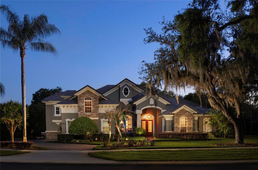 Welcome to Carisbrooke, an exclusive gated enclave of just 43 estates set on sprawling one-acre homesites within the sought-after Markham Woods Corridor. Surrounded by scenic walking trails, community parks and the refined charm of the Lake Mary lifestyle, this exceptional location offers effortless access to major interstates and beltways, placing world-class attractions, pristine beaches and top-tier regional hospitals all within easy reach. From the moment of arrival, a beautifully maintained landscape, fresh designer exterior paint and an elegant circular drive create a striking first impression, leading to grand custom double entry doors. Inside, a dramatic introduction unfolds as floor-to-ceiling windows to frame serene views of the lanai and resort-style pool, while rich travertine flooring and intricate applied moldings elevate the home’s architectural presence. The interior has been lavishly reimagined with uncompromising attention to detail. The chef’s kitchen is a showpiece, appointed with Sub-Zero and Thermador appliances, bespoke cabinetry and exotic granite surfaces. Distinctive design elements, including an Invisacook cooktop and a Waterstone copper faucet set above an impressive 42-inch sink, create both visual intrigue and functional excellence. The adjoining family room, anchored by a custom-built entertainment center, flows seamlessly to the outdoor living spaces. The primary suite is a private retreat, offering rich hardwood flooring and a beautifully renovated spa-inspired bath designed for relaxation and indulgence. The private office enjoys a built-in closet with the versatility of a possible fifth bedroom if desired. Two additional bedrooms are thoughtfully positioned on the main level and share a jack-and-jill bath, while the fourth bedroom and a generously sized bonus room upstairs provide exceptional flexibility for lifestyle, entertainment or leisure. Outdoors, the experience continues with a newly installed limestone paver pool deck overlooking an expansive, meticulously manicured backyard. A striking 10-foot granite fire pit and a custom pergola set the stage for unforgettable evenings under the stars. Completing the residence is an oversized three-car garage with extended driveway parking, along with new mechanical systems, updated designer fixtures and whole-house audio, delivering a turnkey, move-in-ready estate defined by luxury, comfort and incredible Florida lifestyle.