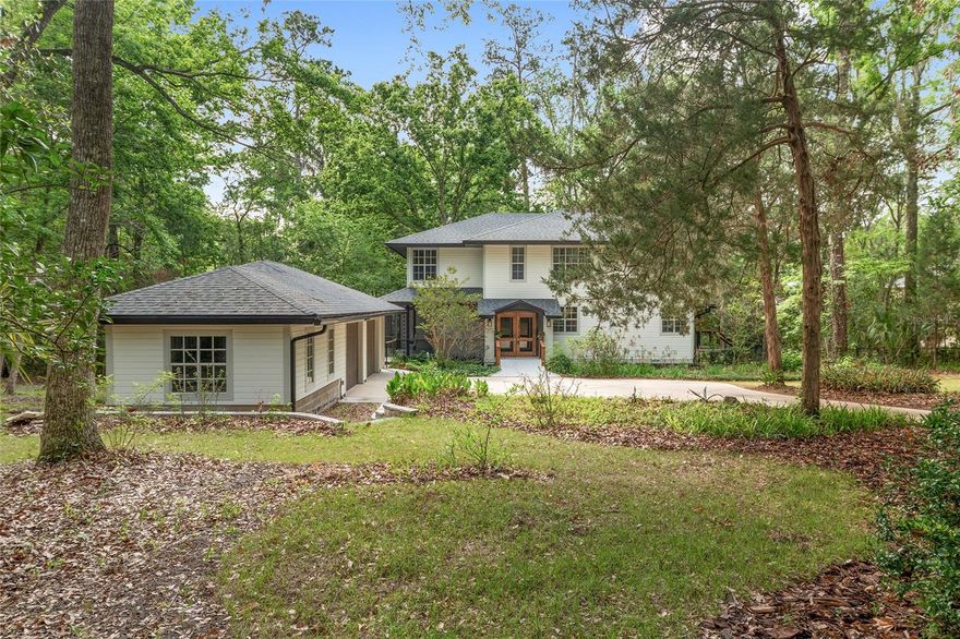 Located in the Park Avenue neighborhood, west of Park Avenue off 60th Street, this 4-bedroom, 3-bathroom home offers 2,531 square feet of renovated living space. Hardwood floors and a wall of windows run throughout, framing views of the wooded backyard and deck. The remodeled kitchen features quartzite countertops, an induction cooktop, new cabinetry and pantry, two sinks, soft-close drawers, new tile flooring and built-in bench with eat-in table. The family room centers around an electric fireplace with integrated lighting, built-in cabinetry for an under-counter refrigerator and wine shelving. A separate formal dining room completes the main living area. The custom staircase includes built-in library shelving, a cherry wood countertop and recessed lighting. A first-floor bedroom has a fully renovated en-suite with Schluter waterproof membrane, tile walls and flooring, wall-mounted toilet, custom shower with built-in bench, new vanity and pocket door access. A dedicated laundry room rounds out the main level.  Upstairs, the primary suite features a renovated bath with Corian countertops, dual sinks, soaking tub, Schluter waterproof walk-in shower with a half-wall,  tile throughout. The bedroom includes a custom cypress epoxy desk, built-in shelving and cabinetry, a feature wall and new lighting. The walk-in closet has custom cabinetry and a full storage system. Two additional bedrooms share a remodeled bath with Corian countertops, tile floors and walls, and a Schluter waterproof shower enclosure. The rebuilt rear deck offers staircases on both sides, a tongue-and-groove soffit ceiling, cable railings, fans, lighting and ceiling-mounted Bluetooth speakers. Exterior updates include new paint, 3-zone irrigation, gutters with rain chains, a concrete patio behind the garage, a retaining wall with steps in front and new garage doors with openers. Mature grapefruit and tangerine trees, two new HVAC systems and a solid pier foundation round out this property. Minutes from North Florida Hospital, the University of Florida, I-75, and top-rated schools.