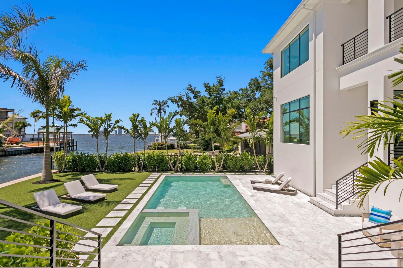 Davis Islands Unrivaled Luxury. Coastal Modern 2023 built waterfront construction boasting spectacular views and breathtaking sunsets on one of the neighborhood’s most sought-after streets. Extensively upgraded by the current owners after initial construction, enjoy the perfect slice of paradise throughout this waterfront masterpiece with superior craftsmanship, open bay views and deep-water dock on over 100 ft of water frontage. Built to the latest building codes with concrete block construction, impact windows/doors, and elevated FEMA-compliant living for flood risk reduction and optimal insurance premiums. From the impressive pivot glass door entry, you’re greeted by a two-story grand foyer, glass walls and expansive light filled living spaces. With refined finishes, stunning hardwood floors and designer lighting throughout plus full retracting glass doors from the great room to the covered terrace beyond. Offering a sleek dual island chef’s kitchen with Wolf/Sub-Zero appliances, Miele coffee station and adjacent catering kitchen, and water view dining and glass enclosed wine room. The first level also offers an ensuite guest room, an additional waterfront guest suite and one of two laundry rooms. Your choice of a convenient 3-stop elevator or sleek stairway lead to the second level featuring an elegant primary retreat with full morning bar, custom his and her closets, tray ceiling, expansive water views and a private terrace. The luxurious bath boasts a deep soaking tub and generous glass shower with dual shower heads. The second level includes 3 additional ensuite guest rooms, an expansive media/bonus room with entertaining wet bar and private bath, along with a second laundry room. The very best of Florida waterfront living awaits outdoors with the designer saltwater pool and spa, elegant marble pool deck and generous covered terrace for entertaining with a gas fireplace, full outdoor kitchen, waterfall-edge island, plus large living and dining areas overlooking the water. A 3 Car garage with recent buildout can also accommodate future lifts for car additional storage. Minutes to the Open Bay, the yacht-ready full-service dock, along with power/water and lighting for the best of boating any time of day or night. Additional upgrades by current owner include a whole home generator, smart home technology, advanced AV and blinds system, upgraded door package and designer lighting throughout, dock upgrades plus an extensive mature tropical landscape and landscape lighting system package. The envied Davis Islands lifestyle provides a vast array of recreation both on and off the water. Residents enjoy a yacht club, private airport, tennis complex, community pools, Davis Islands Beach, parks and more. Offering A-rated schools and convenience to endless recreation, Water Street and Riverwalk, sports venues, shopping, dining and entertainment, come home to Ultra Luxury and the epitome of exceptional Waterfront Living in the heart of South Tampa. Note: Owner invested in significant upgrades and enhancements since purchase.