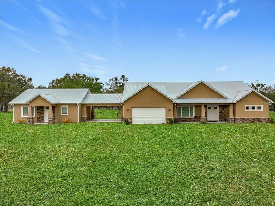 Spectacular opportunity awaits! This custom-built home, completed in 2020, features a separate apartment/in-law suite and sits on a fully fenced 10-acre lot with electric gated entrance. With two distinct residences and a massive 30X65 commercial-grade workshop, this property is just minutes from the world-renowned World Equestrian Center (WEC). Whether you’re seeking space, income potential, or a prime location, this farm is an ideal choice. Located on a paved road with no HOA restrictions. Short Drive to both HITS and the World Equestrian Center, and moments from the natural beauty of Rainbow Springs.
Professionally designed for efficiency, this unique property offers several income-generating possibilities. Live in one home and rent out the other (Airbnb/VRBO) for excellent returns or consider adding an RV hookup to welcome guests. The main residence features 3 bedrooms +office. This home impresses with a grand entrance featuring stone accent columns with a cozy front porch. Step inside to a stunning living room with coffered 10’ ceilings, expansive built-in electric fireplace surrounded by tile with tile backsplash wall and sliding doors leading to the back lanai. 30x30 porcelain flooring and 8’ doors add a touch of luxury, while the chef’s kitchen boasts a Wolf induction cooktop, double oven, Bosch dishwasher, a separate coffee bar area, lots of soft-closed cabinets, and expansive granite counters with a gorgeous waterfall edge island.
The private master retreat includes dual walk-in closets and a luxurious bathroom with an all-glass walk-in tile shower. Spacious second and third bedrooms share a well-appointed bathroom. A breezeway connects the main home with travertine tile to the in-law quarters, where you will find travertine tile throughout the home. This home offers two bedrooms, two full bathrooms, a comfortable living room, and a complete kitchen with soft-closed cabinets, granite counters, and is designed for ADA accessibility—perfect for multi-generational living or rental income.
The commercial-grade workshop is built on solid concrete, is insulated and offers (2) 14 ft roll up doors. This shop comes equipped with a 3-ton lift extended the length of the shop, an Atlas 7 ½ horsepower screw compressor with dryer, twin double amp panels, 100-amp breaker disconnect, and is wired for 3 phase, providing ample space for hobbies, storage, or a small business. The property is nestled in a quiet, equestrian-friendly neighborhood that’s ideal for riding both on and off the premises. Outdoor enthusiasts will appreciate proximity to Goethe State Forest for horseback riding, hiking, and wildlife viewing, as well as the nearby Rainbow Springs State Park for kayaking and swimming.
This spacious country retreat is packed with modern amenities and unmatched outdoor access. It’s conveniently located near Dunnellon, Ocala, Gainesville, Bronson, and Cedar Key, with easy access to HITS, WEC, and Blk Prong Equestrian Village for horse events, entertainment, restaurants, and additional amenities. If you’re searching for a unique blend of tranquility, versatility, and opportunity in the heart of Florida’s horse country, this property is a true must-see!