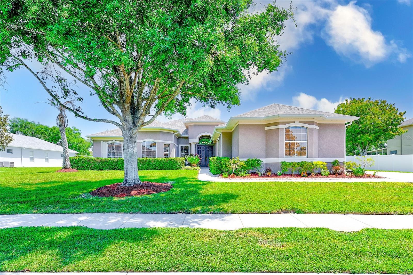 Elegance meets functionality in this impeccably maintained 5- bedroom, 3-bathroom pool home with dedicated office and a 3-car garage nestled on a nearly half an acre in the gated community of Magnolia Estates. From the grand entryway with custom tray ceiling to the seamless indoor-outdoor flow, every detail of this home is crafted for comfort and sophistication. The open-concept layout is adorned with soaring ceilings filled with natural light and architectural built-ins. The gourmet kitchen boasts 42” cabinetry, stainless steel appliances, double wall ovens, ample counter space, and a casual dining nook, complemented by a formal dining room nearby. The luxurious primary suite is a true retreat with a sitting area, private pool access, and a spa inspired bath with dual vanities, walk-in shower, soaking tub, and oversized walk-in closet. The versatile office/den adds flexibility for today’s work-from-home lifestyle. French pattern travertine flooring extends throughout all five bedrooms and the office. One of the bedrooms boasts a private bathroom and walk-in closet making it an excellent in-law suite option. Step outside to a private oasis with a screened-in and heated Pebble Tec saltwater pool and spill-over spa (2015), plus a professionally installed putting green (2023). The oversized lot on 0.47 acres offers lush landscaping, no rear neighbors, and a 3-car garage with epoxy floors, Tesla charger, and custom storage system. Recent upgrades include: NEW ROOF (2023), white vinyl fencing (2023), water heater (2020), pool safety fence (2020), dual HVAC systems (2015), and water softener (2016). Enjoy exclusive amenities with a family-friendly playground, fishing pier, and private community boat ramp with access to Anclote River and the Gulf. Zoned in top-rated schools, in a NON-FLOOD zone, with low HOA fees and close to shopping, restaurants, medical facilities, golf courses, and beaches. This home offers the perfect blend of luxury, comfort, and lifestyle!