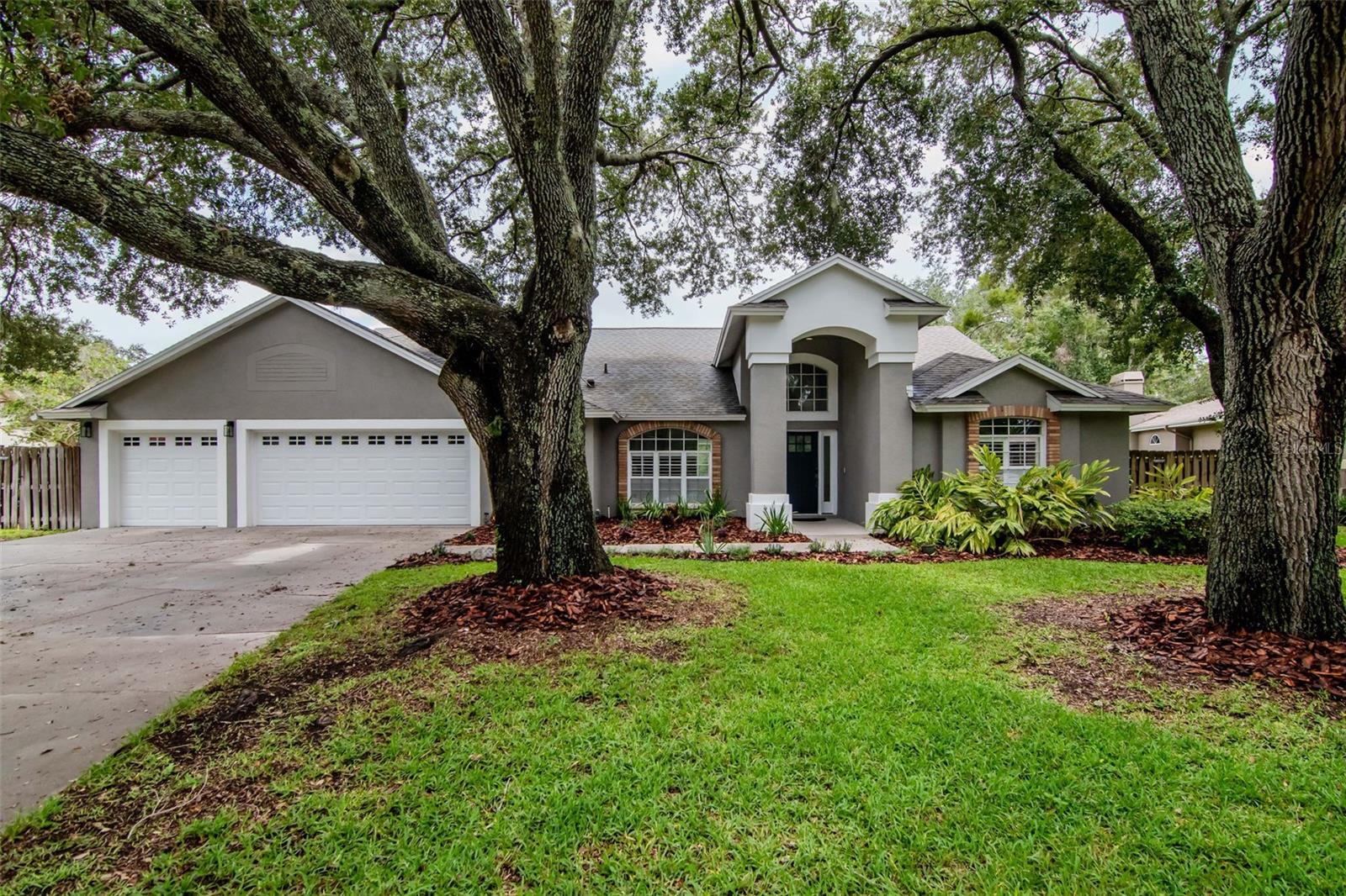 This is the Florida pool home you’ve been waiting for—where comfort meets design, and every inch feels like home. Tucked away on nearly half an acre in one of Lutz’s most exclusive guard-gated communities, this 5-bedroom, 3-bathroom stunner is all about space, style, and serenity. With a layout perfect for multi-gen living, entertaining, or just stretching out and living large, this home checks all the boxes.
Inside, you’re greeted by soaring ceilings, wide-open spaces, and luxury vinyl plank flooring throughout the main living areas. The dining room is bright and airy, while the fully updated kitchen steals the show—think quartz countertops, sleek gray cabinetry with crown molding, a butcher-block buffet, stainless LG appliances (2024), wine fridge, statement lighting, a giant storage island, and a gorgeous pass-through to the living room, all lit by a warm skylight above. The family room brings the cozy with a wood-burning brick fireplace, rustic wood beam mantel, built-ins, and upgraded sliders that open wide to the outdoors. Whether it’s a dinner party or a Netflix night, this space is made for connection. The split-bedroom layout is designed with versatility in mind. The primary suite features vaulted ceilings, a walk-in closet, plantation shutters, pool access, and a spa-inspired en-suite with marble counters, soaking tub, tiled shower, and a dreamy chandelier. An attached bonus room adds flexibility as a home office, 5th bedroom, nursery, or zen space. Two more bedrooms + a remodeled full bath sit behind a pocket door for extra privacy, and there’s another tucked-away bedroom with its own poolside bath—ideal for teens, guests, or in-laws. A fifth bedroom near the primary is perfect for your next creative studio or office. Outside? Your own private oasis. A screened saltwater pool and spa with waterfall, covered lanai, ceiling fan, and lush fenced backyard await. The massive oak tree, gazebo, and shed (with concrete pad and hurricane straps) add both charm and function. There’s a separate side yard for pets or play—and even space to park your boat. Upgrades include a newer roof (2021), NEW AC (2024), water heater (2018), mini-split A/C in the garage (2021), epoxy floors (2022), custom shelving, and a water softener system. All in a flood zone X—no flood insurance required. Located in the beloved Manors at Crystal Lakes, this home comes with all the perks: 24/7 gated security, tennis courts, a playground, and seasonal neighborhood events that bring the whole community together. Minutes from shopping, dining, the Veterans Expressway, I-275, Tampa Premium Outlets, and more. Homes like this don’t come up often—especially not with this level of care, character, and space. Don’t sleep on it—schedule your private showing today!