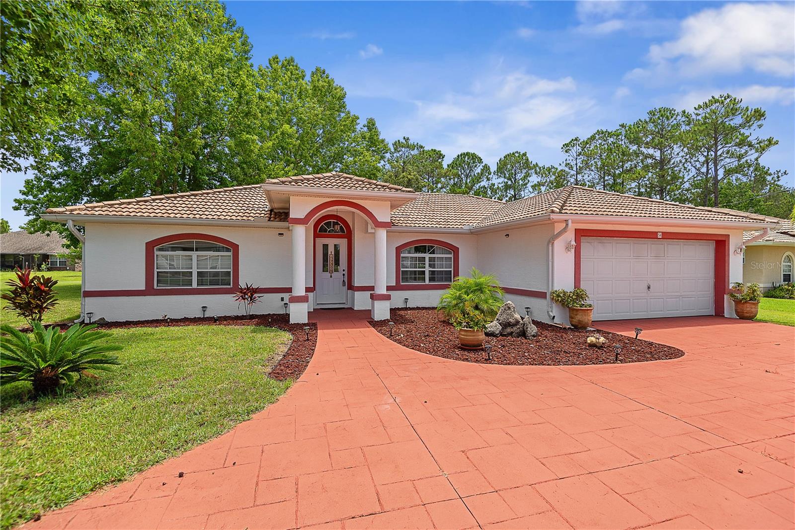 From the moment you arrive, this home welcomes you with a circular driveway, low-maintenance landscaping, and a warm, inviting feel. Step inside to find natural light pouring in, highlighting the open layout and easy flow of the main living spaces.
Tile flooring runs through the main areas, while the living room and bedrooms feature vinyl floors for a soft, modern touch. The kitchen is nicely equipped with stainless steel appliances and opens to the dining area, where sliding glass doors lead to a covered lanai—ideal for morning coffee or evening gatherings.
The spacious primary suite includes a bathroom with double sinks and plenty of room to relax. Outside, the fully fenced yard offers space to play, garden, or unwind.
With a tile roof, well-kept interiors, and great outdoor space, this home is move-in ready and full of charm.