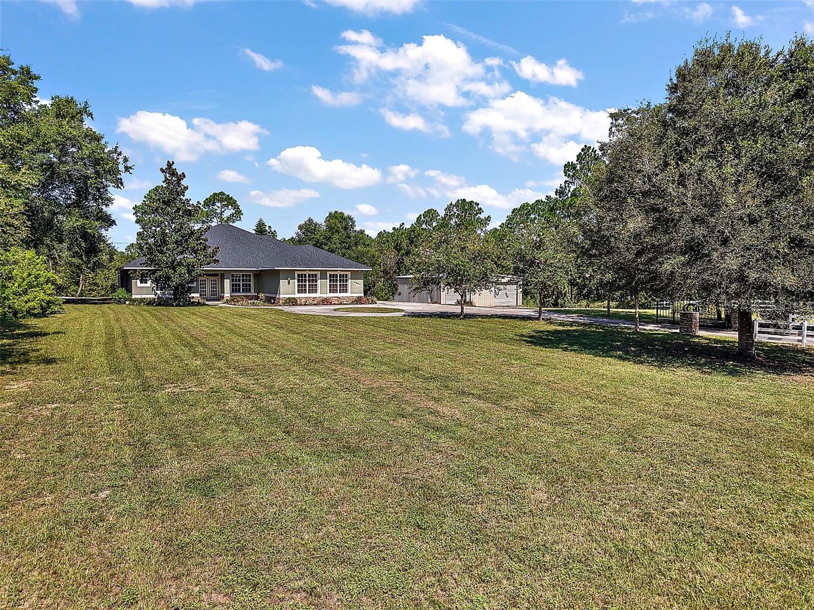 Welcome to 21097 County Road 455 A turnkey estate on nearly 4.8 gated and cross fenced acres in one of Clermont’s most sought after rural settings. This private property offers the perfect mix of rural living and modern convenience, complete with a new roof 4/28/2025 and an outdoor security system with a private gated entrance. Step inside to an open floor plan featuring updated appliances in the kitchen, a wrap around bar, hardwood cabinets and solid granite countertops, a spacious Primary Bedroom with a large en suite bathroom and French doors leading to the screened pool area. The living room also features French doors that open to the pool space, creating a
seamless flow for indoor/outdoor living. An additional exterior door provides direct access to a bathroom, perfect for poolside guests.
Enjoy your own backyard retreat with an outdoor kitchen/built in grill area, screened in pool and a gazebo with a fire pit, ideal for relaxing.
Car enthusiasts will appreciate the 40x40 workshop with a two-post car lift, offering excellent space for projects or storage. The property is fully cross fenced, making it suitable for animals, equipment, or added privacy. Located just minutes from downtown Clermont and Montverde, and with Hancock Road soon connecting directly to CR-455, this home provides a quick and easy commute to Orlando, plus convenient access to FL-50 and the Turnpike. With no HOA and every feature in place, this move-in-ready property is ready to welcome you home.