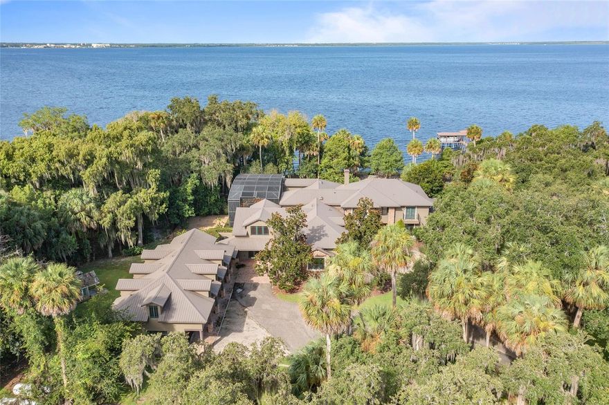 Nestled among centuries-old grandfather oaks along the northern shore of Lake Monroe, one of Central Florida’s largest lakes with Intracoastal Waterway access via the St. Johns River, resides the incredible "Grand Pointe," a privately gated icon estate built in 1998 by renowned homebuilder Charles Clayton. Reminiscent of the lodges of our National Parks in the western Rocky Mountains, the grandeur of stone and wood engender timeless elegance. Grand Point resides on one of the highest points of Stone Island, set ideally on 3.5 acres and located just moments from the Orlando, the beaches, three international airports and the vibrant historic downtowns of Sanford and DeLand. Take a short boat ride across the lake to the farmers market, brunch, dinner or the coffee shop right from your private boathouse or meander up the St. Johns River toward the Intracoastal Waterway. Enjoy 425 feet of undisturbed shoreline from within the private shade of a canopied landscape and manicured lawns overlooking a tremendous boathouse featuring dual boat lifts and seating area. The estate boasts a main residence with five bedrooms, a fantastic office, five full baths plus two half baths, two bonus rooms and a game room. Enter the grand foyer to experience 24-foot floor-to-ceiling windows offering cascading views of the lake from the living room then roam into the enormous family room which offers incredible views of both the pool and lake. Exquisite woodwork and craftsmanship are evident. The generously sized chef’s kitchen offers professional appliances, a large casual dining space and opens to the family room. Entertain family and friends in the two-story lanai or the first-floor game room with pool access. The private lakefront office with fireplace makes working from home a pleasure while the near 500-square-foot laundry makes day-to-day chores a breeze. The first-floor master suite is a lake-view oasis of its own while the upstairs bedrooms and bonus rooms upstairs, complete with a Walt Disney World princess hideaway round out this incredible estate. Multiple balconies and terraces extending the resplendent living spaces of each level of the home. Follow the breezeway to the carriage house featuring a car enthusiast's climate controlled four car garage car enthusiast’s four-car garage with high ceilings, ample storage and a half bath. Above resides a near 1,500-square-foot guest-suite, current set up as a classic study. The outdoor lifestyle offers an abundance of activities via the lakefront fire pit, the private boat dock with lifts, the pool and spa with two-story screen enclosure, all connected by brick paver walkways. The home is protected by a commercial-sized whole-house generator fueled by dual 1,000-gallon propane tanks providing weeks of backup power. Located near Interstate 4, the 417/429 beltways, easy access to Orlando International and Daytona Beach international airports, the attractions and the beaches makes Grand Point a once-in-lifetime opportunity.