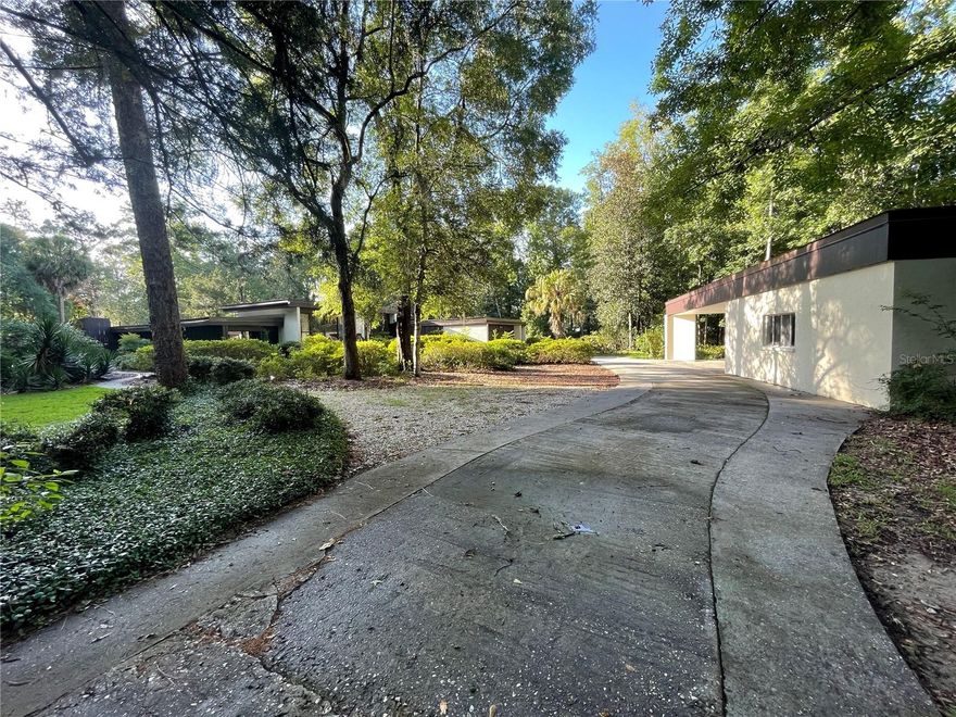 Stunning 3-bedroom, 3-bathroom estate with a dedicated home office offers over 4,000 sq ft of beautifully maintained living space in a peaceful, private setting—just 15 minutes from UF, shopping, dining, and entertainment.
Set on over 5 acres along Millhopper Creek, this mid-century modern masterpiece combines timeless architecture with high-end amenities. The home features soaring ceilings, expansive floor-to-ceiling windows, and natural views that create a seamless indoor-outdoor connection.