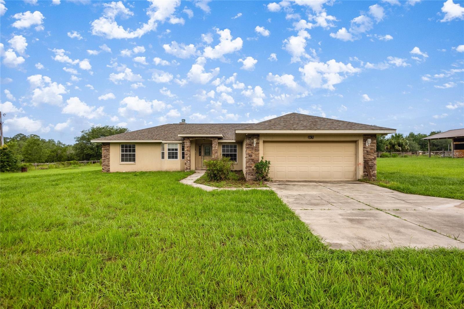 Welcome to your personal slice of country living — just minutes from modern conveniences! This meticulously maintained 3-bedroom, 2-bathroom home offers 1,690 sq ft of thoughtfully designed living space on 3.28 acres of fully cross-fenced, A1-zoned land — ideal for horse owners, homesteaders, or those simply seeking serenity with room to grow. As you enter, you’re greeted by vaulted ceilings that create an open, airy feel throughout the main living areas. The entire home features neutral-toned tile flooring, making it both pet-friendly and easy to maintain. The spacious living room centers around a charming wood-burning fireplace, perfect for cozy nights and relaxed gatherings. The kitchen is conveniently laid out for both everyday cooking and entertaining, with ample cabinetry and countertop space. A bright dining area offers beautiful views of the property, making every meal feel like a retreat. The split-bedroom floor plan provides privacy and space for everyone. The primary suite is a true retreat, featuring his-and-her sinks, a luxurious jacuzzi soaking tub, a walk-in tiled shower, and a large walk-in closet. The two additional bedrooms are generously sized and share a well-appointed second bathroom. Brand new A/C unit (2025) for energy-efficient cooling, New architectural shingle roof (2024). Tile throughout – no carpet anywhere, Outdoors, the property is ready for your horses or livestock. It includes: Two spacious paddocks, A 12x12 two-stall shed-row barn, each stall with room to move and relax, A dedicated tack room for storing feed, gear, and supplies, Fully cross-fenced to keep animals safe and secure. The 2-car garage provides plenty of room for vehicles, tools, and storage. There’s also space for trailers, RVs, and outdoor equipment. Only minutes from Lake Weir, where you can enjoy boating, fishing, and lakeside dining, Close to local eateries, shopping, medical facilities, and Highway 441, A quick 30-minute drive to Ocala and the famous World Equestrian Center, Just 1 hour to Orlando and its world-renowned attractions, Convenient to The Villages for additional dining, shopping, and golf options. This property blends the best of peaceful rural living with proximity to everything you need. Whether you're an equestrian enthusiast, a growing family, or simply looking to escape to the countryside without giving up convenience — this home has it all. Schedule your private showing today and come experience the lifestyle you've been dreaming of!