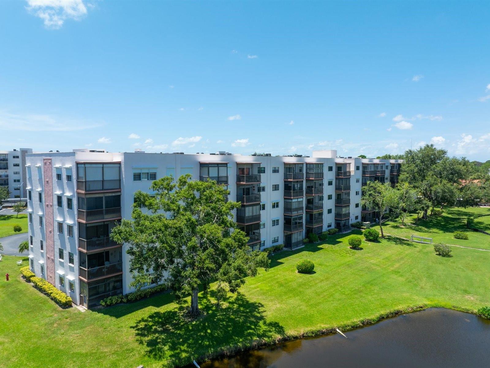 Top 5th-floor 2bed/2bath w/spectacular views facing east/Sunrise to a large pond w/a fountain from the large screened porch. This split floorplan offers new(2015)PGT Hurricane Impact windows and sliding glass doors& an upgraded custom electric shade for the sliders too. The kitchen has been tastefully renovated w/Corrian countertops, seamless double sink, GE side/side refrigerator & dishwasher(2024), and a Samsung microwave(2023). The full-size washer/dryer are located off the kitchen w/additional space for storage or an office area. The ($893)monthly fee includes water, sewer, garbage, gas & exterior amenities. One covered parking spot & ample additional guest parking available. Five Towns is an active 55+ resort style community w/over 144+acres, of walking paths, ponds, several pools, tennis courts, grilling pavilions& an abundance of wildlife! The Tiffany Bldg is one of the few that offer a "secured" lobby w/elevator access. Just minutes to Publix, Target & tons of restaurants including Bonefish Grill, Carrabba's & Texas Roadhouse. Meticulously maintained by the same owners since 1998.