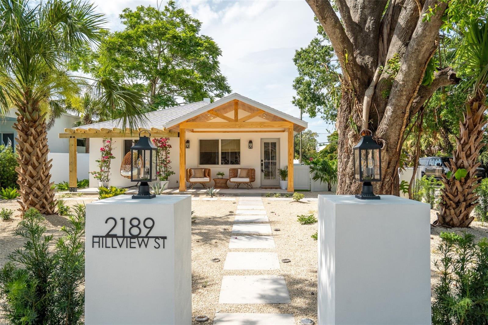 Welcome to this stunning modern coastal cottage on coveted Hillview Street, ideally positioned on a corner lot in Sarasota’s Arlington Park neighborhood. Over 1700 Sq feet of indoor and outdoor living space the home has ben completely renovated top to bottom in 2025, all-new hurricane impact-rated windows and doors, paired with a brand-new roof, provides peace of mind, and storm protection for years to come. This fully renovated 3-bedroom, 3-bath home with multiple outdoor living areas, offers the ultimate in Florida lifestyle living.
From the moment you arrive, you’ll be captivated by the beautifully designed approach, new low maintenance coastal desert landscape, modern concrete pavers guide you from the street to the front porch, framed by lantern-topped concrete posts and a lush living hedge of newly planted Podocarpus that gracefully wraps the corner perimeter, the turfed side yard offering both privacy and polished curb appeal. The custom millwork gable porch in warm pine, sets the tone for the home’s inviting coastal aesthetic. The Mediterranean pergola creates a taste of Europe with an inviting entry, perfect for the trailing bougainvillea to bloom and soften the architectural lines.
Step inside to a naturally bright and open living space, where a large picture window floods the interior with light and frames serene views of the landscaped front yard. The open concept living space flows effortlessly to the new kitchen which features all-new white classic slim shaker cabinetry, brushed brass hardware, new stainless steel appliances, a marble porcelain backsplash, open custom shelving, and signature shiplap all centered around a sit-in island bar ideal for gathering — perfectly curated to reflect a balance of modern design and timeless coastal charm.
The large primary suite is a true retreat, with sliding doors that open to a private screened-in lanai overlooking the new pool area. The en-suite bath is designed for tranquility, showcasing polished travertine tile, fluted accent tiles, and chrome fixtures—a spa-like oasis of refined serenity. Two additional bedrooms are generously sized and versatile, perfect for guests, a home office, or creative studio space. Two brand new bathrooms perfectly curated with tiles and finishes to accommodate these lovely spaces.
Outdoor living is unmatched, with three private areas for relaxation and entertaining, covered front porch for lounging and sunset views, a turf-covered side yard, ideal for alfresco dining under café lights, kids’ play, or a pet-friendly space, backyard with pool and screened lanai for effortless Florida lifestyle. Multiple parking spaces making it convenient for visitors and guest.
Located walking distance to Arlington Park, Morton’s Market, Southside Village, restaurants, shops, Sarasota Memorial Hospital, and a drive over to Siesta Keys Beach this home offers the perfect blend of charm, lifestyle, and investment opportunity. With a high rental income potential, it’s ideal as a primary residence or high-performing vacation rental.
This home may be smaller but it lives large—with thoughtful design, timeless charm, and an unbeatable location, this is a rare find schedule your showing today!