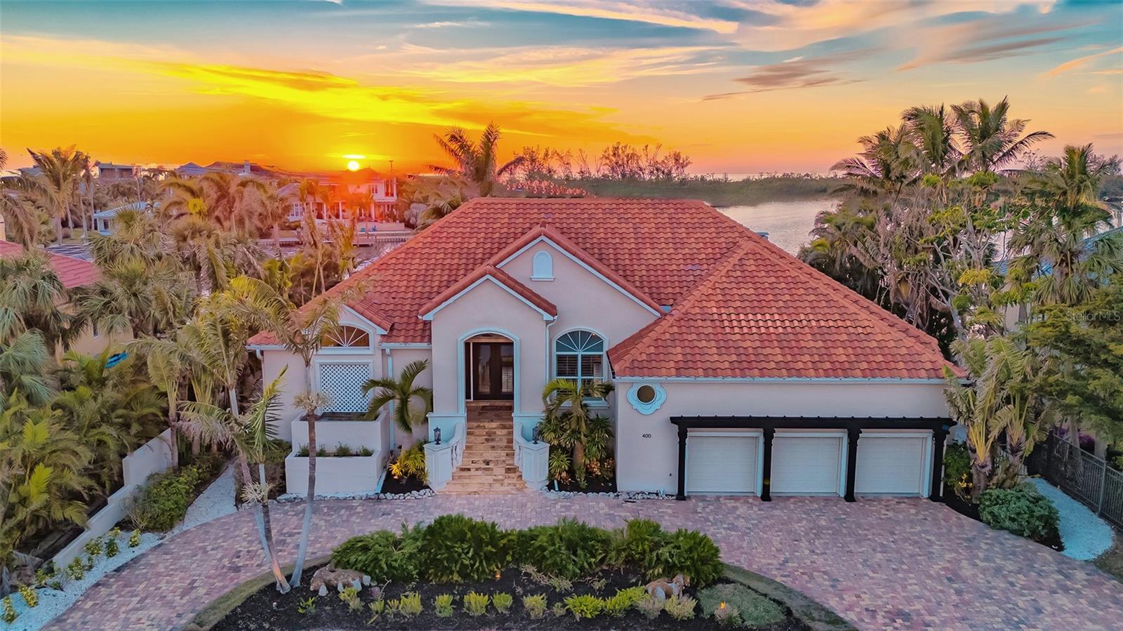 Just two blocks from the world-class shopping and dining of St. Armands Circle and Lido Beach, this luxurious hurricane and FEMA-complaint coastal retreat is designed for safety and elegance, with the main living level elevated 11.4 feet above base flood elevation (exceeding FEMA base flood elevation). Set against the serene backdrop of Pansy Bayou, with 110’ of waterfront, the immaculate residence is surrounded by the beauty of nature, across from a bird sanctuary teeming with wildlife. Step inside to a light-filled, single-story haven designed for a lifestyle of ease and elegance. Walls of glass throughout invite natural light and panoramic water views indoors, creating an open, airy atmosphere. The split floor plan offers 5BRs, 4BAs plus an office, ideal for both private retreats and staying guests. Entertain in style in the stunning kitchen, complete with all-white cabinetry, harmonizing stone countertops, a large island, premium stainless steel appliances and a wine refrigerator. The kitchen flows seamlessly into the living room, where engineered wood floors add a touch of warmth, and a double-sided gas fireplace enhances the space. The family room’s slider stack opens the home to the outdoors, where a summer kitchen and bar-height seating complete the experience. The primary suite offers a spa-like sanctuary with a large walk-in shower and custom countertops. Outside, a resort-style pool deck with 1,200 sq. ft. of covered and open space invites you to relax and soak in tranquil water views. A spa perched above the waterfall feature spills into the pool below. For the luxury enthusiast, the home also boasts a 3-car garage with space for a car lift, hurricane impact windows and sliders, a whole-home generator, a sound system with speakers throughout and an interior platform lift for easy access to the main living level.