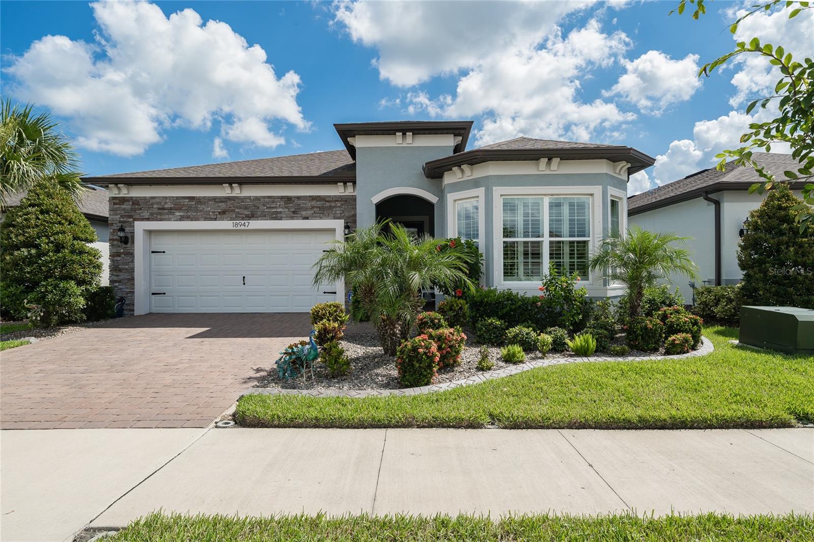 From the moment you arrive, this stunning home makes a lasting impression with vibrant, eye-catching landscaping, a brick paver driveway, stone-accented front elevation, and a charming bay window adorned with plantation shutters. Step onto the covered walkway and through the elegant leaded glass front door, where you're welcomed into a beautifully crafted foyer with detailed woodworking and 8-foot doors that create a grand, open feel throughout.
Immaculate and impeccably maintained, this residence offers effortless living with gorgeous tile floors—no carpet anywhere—making maintenance simple and allergy-friendly. Plantation shutters throughout the home enhance both style and privacy, while 5¼-inch baseboards and custom trim details add an upscale touch in every room. Whether you're seeking a full-time residence or a luxurious second home to escape northern winters, this one checks every box.
The spacious front bedroom functions perfectly as a private guest suite, complete with its own en-suite bath and custom built-in closet. Just down the hall, a versatile flex room with frosted double doors, built-in shelving, and its own closet offers the ideal space for an office, craft room, or even a third bedroom. Storage is abundant throughout, including in the oversized laundry room and in the 2-car garage, which features epoxy flooring and an electric car plug-in.
At the heart of the home, the expansive great room shines with a tray ceiling, recessed lighting, and upscale light fixtures, flowing effortlessly into the gourmet kitchen. You'll find 42" wood cabinetry, a large island, sleek counters, soft-close drawers and cabinets, a stunning tile backsplash, walk-in pantry, KitchenAid appliances, reverse osmosis system, and a water softener—all designed to impress and built to perform.
The serene primary suite is tucked away for privacy and features its own tray ceiling, plantation shutters, and custom woodwork that adds warmth and character. Dual professionally designed walk-in closets provide abundant space, while the elegant en-suite bath offers two sinks and a large walk-in shower with tile to the ceiling.
Step outside to your private outdoor sanctuary, where a spacious L-shaped screened lanai with brick pavers allows for both dining and lounging areas with added privacy screens. For those who love the sun, an additional open brick paver patio with lush landscaping completes the picture. A Generac 200 amp (120/240) whole-house generator offers peace of mind in any weather.
Located in the sought-after Del Webb Bexley, a premier 55+ gated community, you'll enjoy a maintenance-free lifestyle with lawn care included, plus access to a stunning resort-style clubhouse, fitness center, resort pool, pickleball and tennis courts, and a full calendar of social and fitness activities. Conveniently close to major highways, shopping, top medical facilities, and under 30 minutes to Tampa International Airport and downtown Tampa—this home is a rare opportunity that truly stands apart.