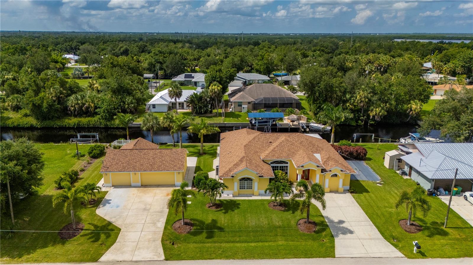 Palm trees sway gently along the canal’s edge, where 160 feet of pristine waterfront set the stage for the ultimate coastal lifestyle- all from this move-in ready 3 bedroom, 3 bath home with detached 3 car garage and a private in-law suite on nearly half an acre. From your private dock-complete with a boat lift-you’re just moments from the open waters of Peace River and onto Charlotte Harbor, a paradise for boaters and anglers alike. This custom-designed home unfolds with thoughtful grandeur. Beautiful wood-look plank tile stretches throughout a bright, open layout tailored for gathering and entertaining. Volume ceilings and crown molding add elegance, while the spacious kitchen commands attention with stone counters, a wine refrigerator, 2020 stainless appliances, a tile backsplash, under-cabinet accent lighting, and ceiling-height cabinetry for extra storage. A breakfast bar and a panoramic-windowed nook offer perfect spaces to start the day-all overlooking serene water views. The main living space flows effortlessly into a cozy family room/den complete with a full bathroom. Down the hall, a large bonus room-currently used as an office-adds flexibility with custom cabinetry down the hall to adapt to your lifestyle. Two additional bedrooms provide comfort for guests or family-one with direct access to the lanai and backyard. Privately tucked away, the primary suite is a retreat in every sense, with a tray ceiling, sitting area, and sliding glass doors that open directly to the lanai. The ensuite bath offers dual walk-in closets, a soaking tub, and a walk-in shower. Step outside to the oversized, tiled screened lanai, a true extension of your living space with screen/projector- ideal for quiet mornings or evening cocktails, all with peaceful water views as your backdrop. Just across the breezeway, a detached three-car garage includes a converted workshop in the third bay- and a private-entry one-bedroom, one-bath apartment with kitchenette, perfect for in-laws, guests, or long-term stays. This home offers more than space- it offers lifestyle. Recent upgrades include a 2025 dishwasher, 2023 AC condenser, 2022 whole-home generator, 2021 well pump, and 2020 roof. Located in Palm Shores, a peaceful, non-HOA community with no deed restrictions, you’ll enjoy rare freedom with a prime location just minutes to Punta Gorda, I-75, and Punta Gorda Airport. For the boater, entertainer, multi-generational household, or anyone seeking privacy and elegance by the water -this home is ready to elevate every day.