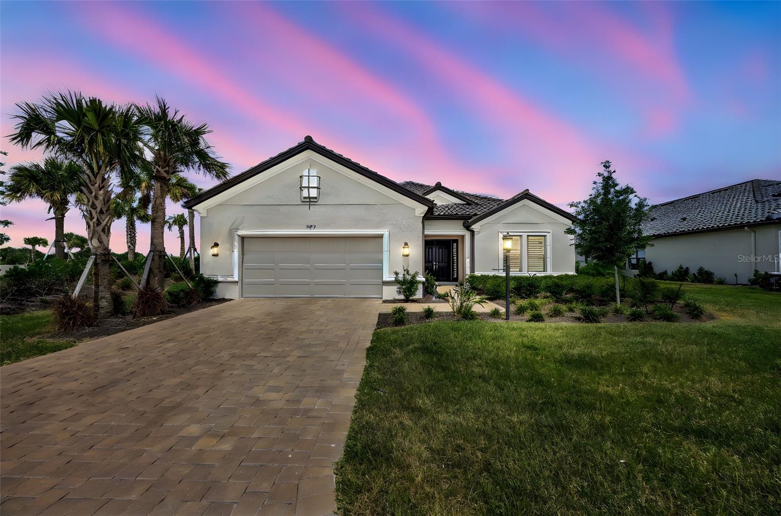 One or more photo(s) has been virtually staged. “SIGNIFCANT PRICE IMPROVEMENT! Taking offers until July 31st so act now—this opportunity won’t last. Contact agent for timing details.” Welcome to your future dream home! This exquisitely upgraded Pallazio model is set on a premier corner lot, offering tranquil water views from the front, a lush park setting in the back, and an expansive easement providing rare privacy between you and your only neighbor. Built in June 2024, this residence presents a rare opportunity, as no more non-golf lots are available to build a Pallazio in Esplanade at Azario. Spanning 3,055 square feet of meticulously crafted living space, this home features 3 bedrooms, 3 full bathrooms, a private office, and a spacious tandem 3-car garage. Light gray premium wood plank tile floors, 8-foot doors, and plantation shutters flow seamlessly throughout, setting a sophisticated tone. The sun-drenched open concept living area impresses with a tray ceiling, expansive sliders, and a striking feature wall with lighted shelving, a sculptural three-sided fireplace, and a floating porcelain hearth. The designer-appointed extended kitchen is a culinary masterpiece, showcasing upgraded white shaker cabinetry, a stylish gray island, sleek quartz countertops, custom pantry shelving, and top-of-the-line GE Gourmet appliances. A thoughtfully designed office with custom built-ins and double pocket doors offers an ideal work-from-home space. The luxurious primary suite is a true retreat, highlighted by a bay window sitting area, an expansive custom closet with built-in drawers, shelving, and slide-out shoe racks, and a spa-inspired primary bathroom featuring an oversized walk-in shower. Two additional guest bedrooms, each with their own full bathrooms, ensure ultimate comfort for family and guests. Step outside to your private extended lanai, perfectly designed for entertaining, complete with a lavish outdoor kitchen featuring a Delta Heat gas grill, griddle, refrigerator, sink, and built-in storage. The space is pre-wired and ready for a custom pool and spa, allowing you to design your personal oasis. Additional highlights include a three-car tandem GARAGE with epoxy flooring, overhead storage racks, and a tankless water heater. Located in the prestigious community of Esplanade at Azario, residents enjoy access to resort-inspired amenities including a sparkling pool, Bahama Bar, Culinary Center, spa, fitness center, golf course, bocce ball, tennis courts, a dog park, community gardens, and more. This impeccably designed home is move-in ready and waiting for you to experience the elevated Florida lifestyle! Non golf home. Seller is flexible on closing date. One or more photos are virtually staged.