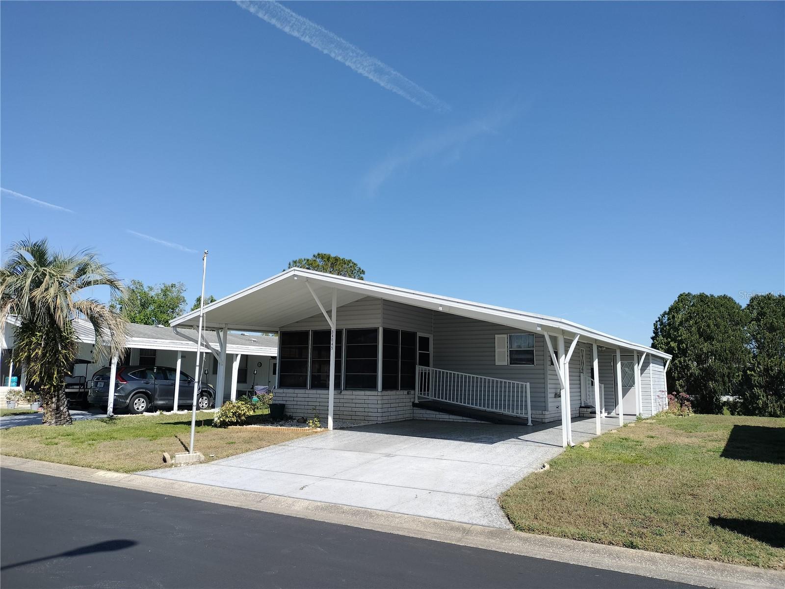BEAUTIFUL MOVE IN READY AND FURNISHED HOME!!! This 2 bedroom 2 bath home is waiting for you. Enjoy this home which sits on a retention pond. This home features a separate Dining area and front screen room. Double carport. The front entrance has a wheelchair or scooter ramp. This home is in a great location with easy access to Wesley Chapel and Zephyrhills. All this and located in a very desirable all aged well kept family oriented community with tons of activities and great amenities some of which include 2 pools, 2 clubhouses, Shuffleboard and basketball court, fishing lake with dock and gated security and YOU OWN THE LAND.