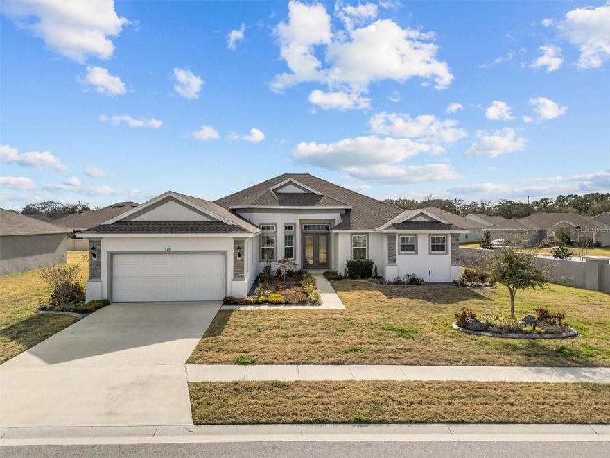 Welcome to this exceptional custom-built 2023 luxury residence located within the gated community of Sanctuary by the Lake, where modern elegance, thoughtful design, and everyday comfort come together seamlessly. Perfectly positioned on a spacious corner lot directly across from the lake, this stunning home immediately impresses with its commanding presence and refined architectural detail.
Step through the beautiful double front doors and experience an immediate sense of openness, highlighted by soaring ceilings, abundant natural light, and expansive living spaces designed to feel both grand and inviting. With over 3,600 square feet of living space, the thoughtfully designed open layout effortlessly connects formal and casual living areas, creating an ideal setting for both entertaining and relaxed daily living.
At the heart of the home lies a beautifully appointed chef’s kitchen, featuring granite countertops, upgraded stainless steel appliances, a breakfast bar, walk-in pantry, and generous prep space, perfect for hosting gatherings or enjoying quiet mornings at home. The kitchen flows naturally into the impressive great room and dining areas, enhancing the home’s seamless indoor living experience.
One of the standout features is the oversized covered and enclosed Florida room, custom added by the owners to extend the living space year-round. Whether hosting celebrations, entertaining guests, or simply unwinding while enjoying peaceful surroundings, this space truly elevates the lifestyle this home offers.
Designed with privacy in mind, the desirable triple split floor plan includes 4 spacious bedrooms, 3 full bathrooms, and a dedicated private office, ideal for remote work or flexible living needs. The luxurious primary suite serves as a private retreat, complete with dual vanities, a garden tub, separate walk-in shower, makeup vanity, and a very generous walk-in closet.
Beautiful luxury vinyl plank flooring flows throughout the main living areas, complemented by tasteful finishes and quality craftsmanship that reflect the home’s custom construction. A well-equipped laundry room with cabinetry, countertop workspace, and sink adds everyday convenience. A 50 amp generator port was added for peace of mind.
Beyond the home itself, the location offers the best of Central Florida living. Just minutes from downtown Winter Haven, residents enjoy award-winning restaurants, local boutiques, parks, and year-round entertainment, while nearby access to Lakeland and I-4 provides an easy commute to both Tampa and Orlando. Florida’s Atlantic and Gulf beaches are approximately 90 minutes away, making weekend coastal escapes effortlessly accessible. This is more than a home, it is a refined living experience combining space, luxury, and lifestyle within one of Winter Haven’s most desirable gated communities.