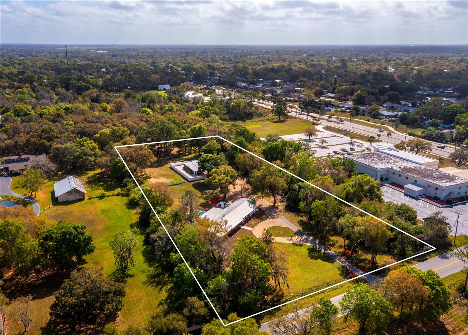 Unlock the potential of this expansive nearly five-acre property nestled in a sought-after part of Sarasota, offering the perfect canvas to build your dream home and create a private oasis for your family. The property features a five-bedroom, 3,800 square-foot home with a refreshing swimming pool, providing a comfortable living space amidst the lush surroundings. The main residence boasts spacious interiors, highlighted by newer impact windows (installed in 2019), a large great room, sunroom, and an eat-in kitchen overlooking a cozy family room with a fireplace. Sleek tile and vinyl flooring, along with wood accents, create a stylish and contemporary atmosphere throughout the home. The private primary suite offers a serene retreat, while four guest bedrooms ensure ample space for family and visitors. Outside, the pool deck provides a tranquil setting for relaxation, enclosed with a safety fence for peace of mind. Situated just minutes away from highway access, the property offers easy commuting while still maintaining a sense of seclusion. Positioned in the path of progress within Sarasota, this expansive estate presents endless possibilities for customization and development. Formerly known as 'The Canine Academy,' this unique parcel of land comes with county approval to operate an on-site kennel, also making it an ideal opportunity for dog enthusiasts or those seeking additional income potential. The professionally designed kennel (updated in 2008), equipped to accommodate approximately 24 dogs, offers added convenience for those interested in canine-related businesses. With amenities such as a grooming area, half bathroom, dog run, and separate office, the kennel is ready to operate smoothly. Don't miss out on this exciting opportunity to create your own slice of paradise in Sarasota. Whether you're looking to build your dream home, operate a kennel, or explore other income-generating ventures, this property offers the perfect blend of privacy, convenience, and potential. Secure your piece of paradise today.